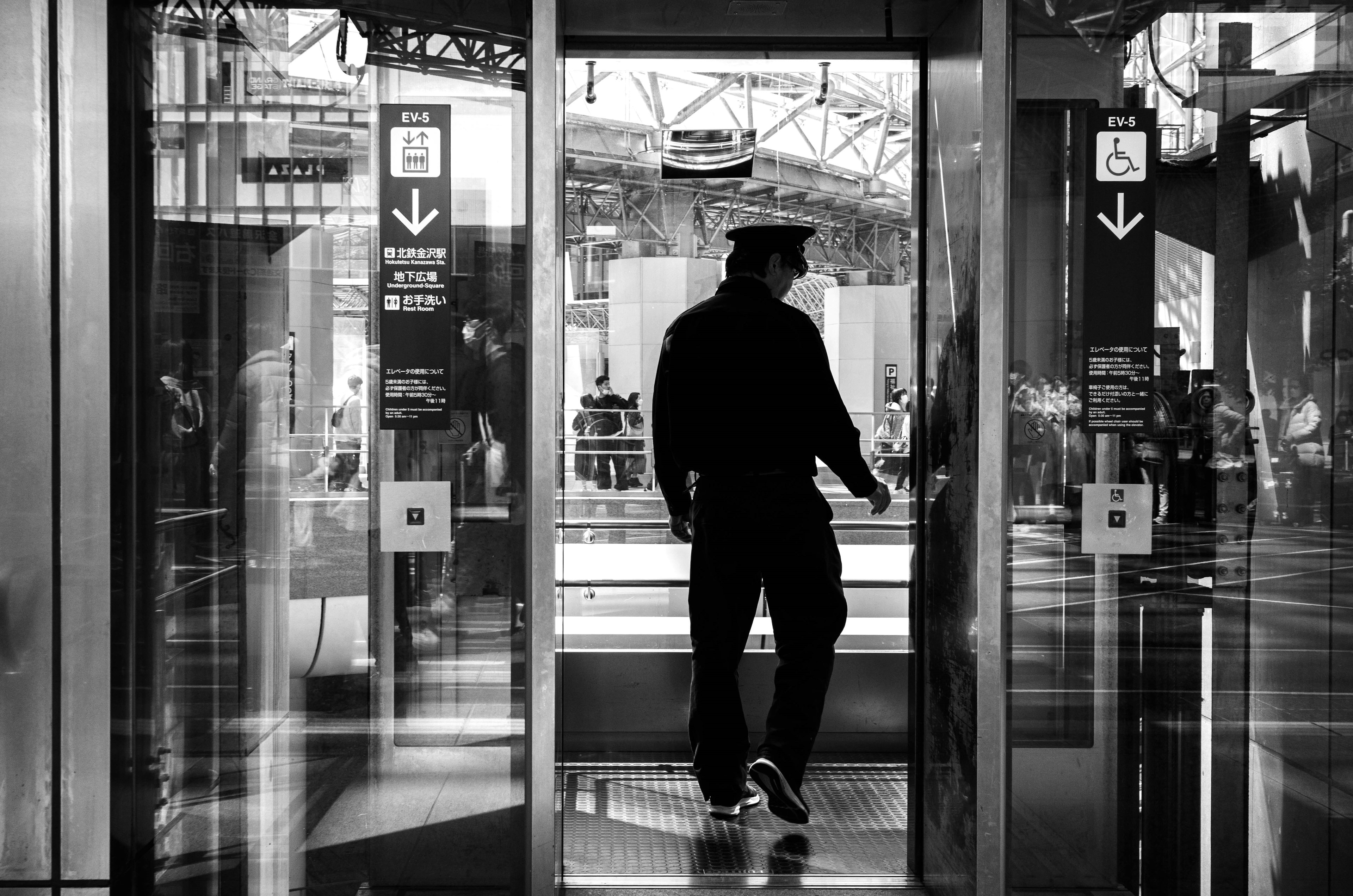 A man in black clothing exiting an elevator