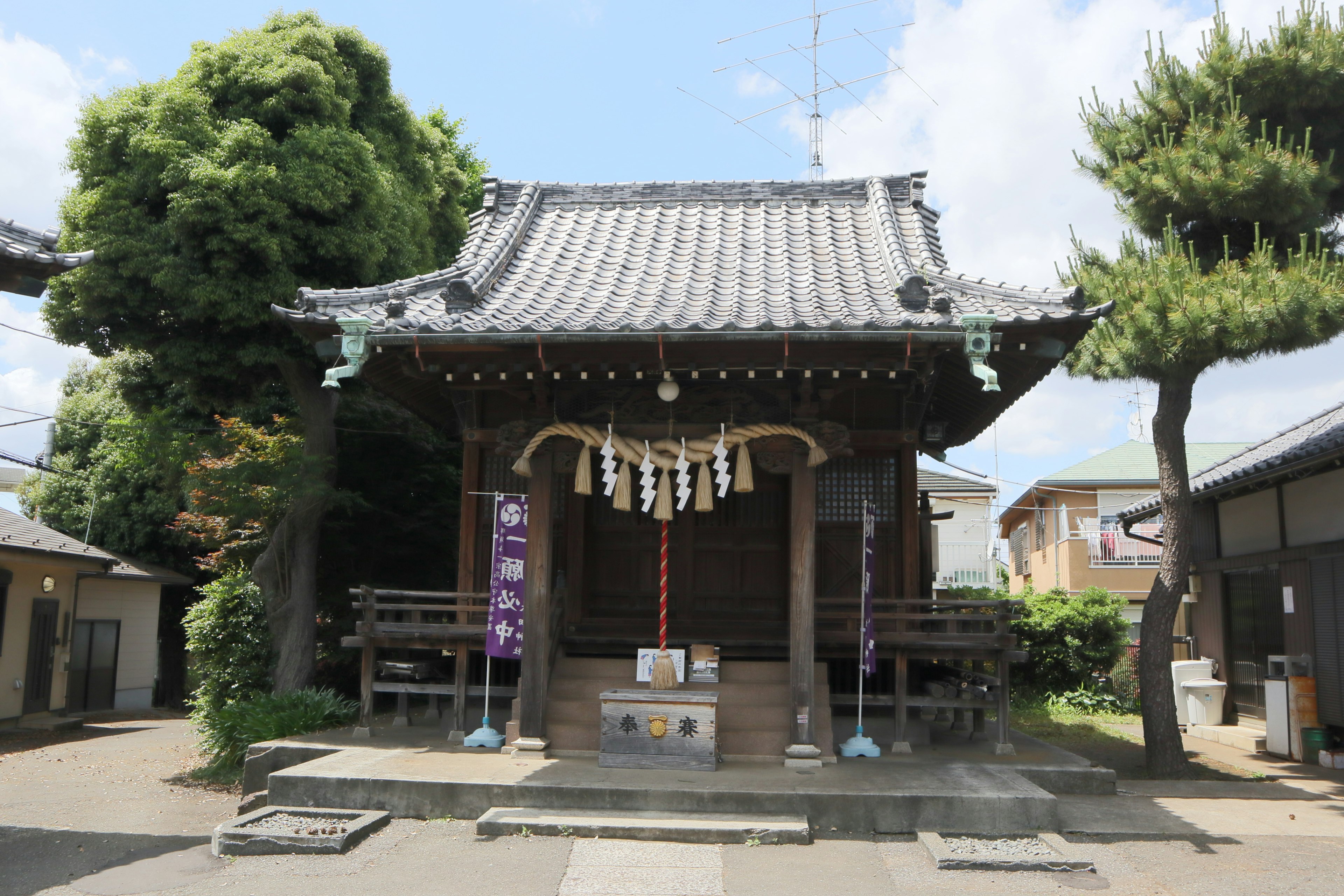 小神社的外觀，周圍環繞著綠色樹木和藍天