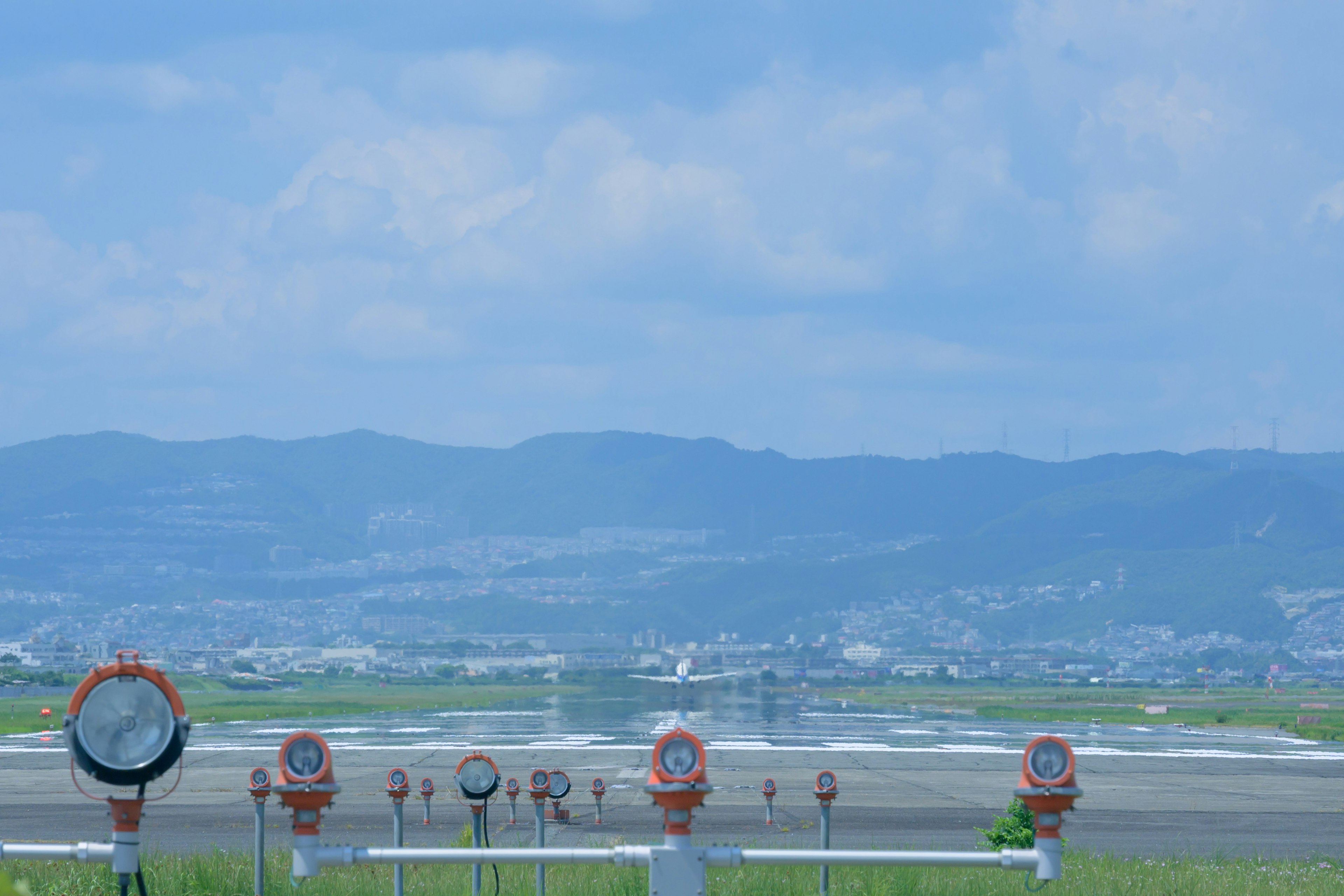 Vista panoramica di una pista d'aeroporto con indicatori di direzione del vento e montagne sullo sfondo