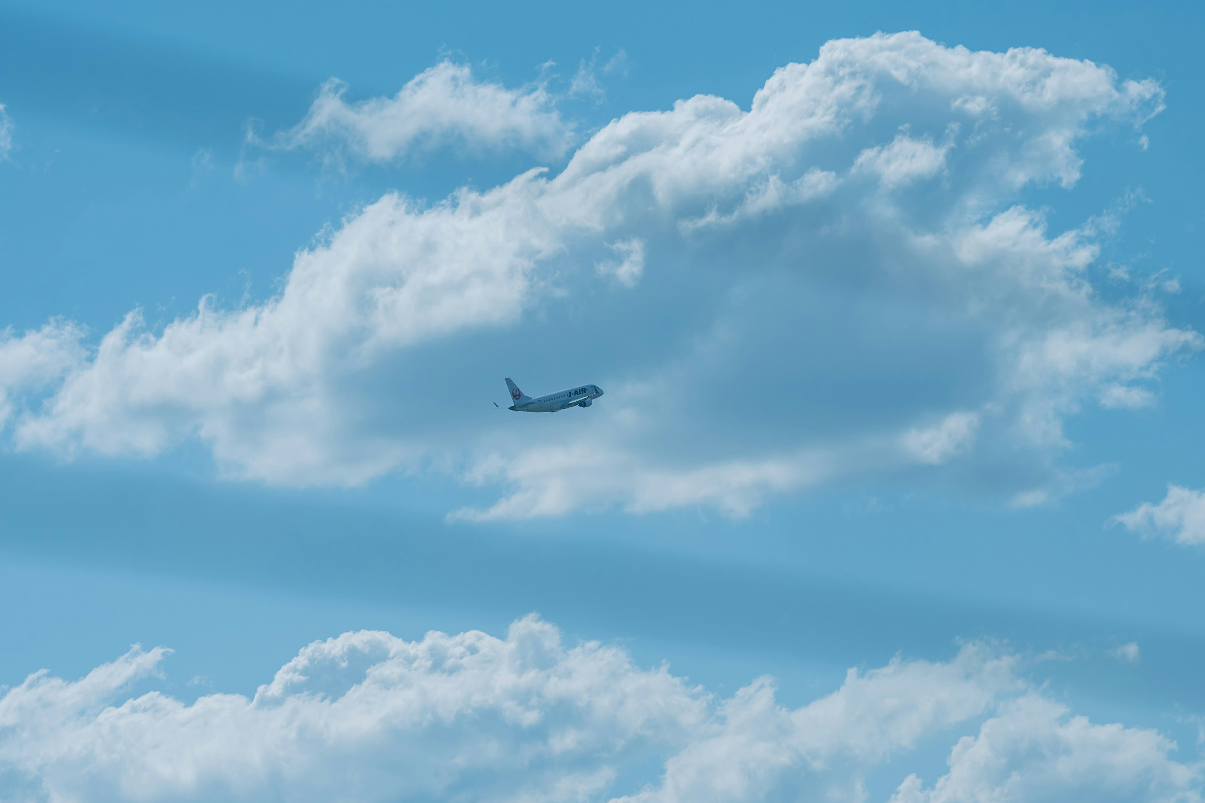 Avión volando en un cielo azul claro con nubes blancas esponjosas