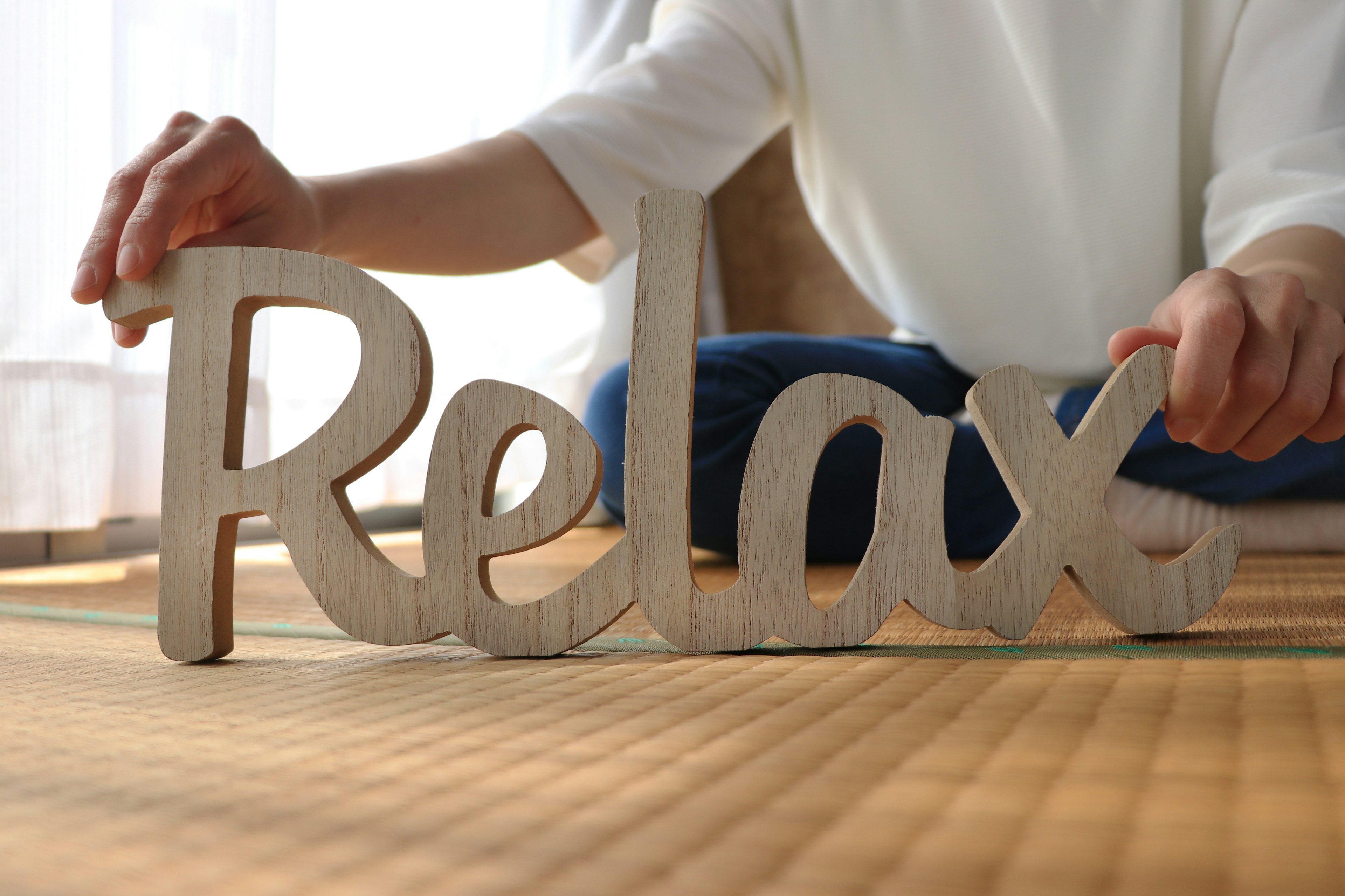 Hands holding a wooden sign that says Relax