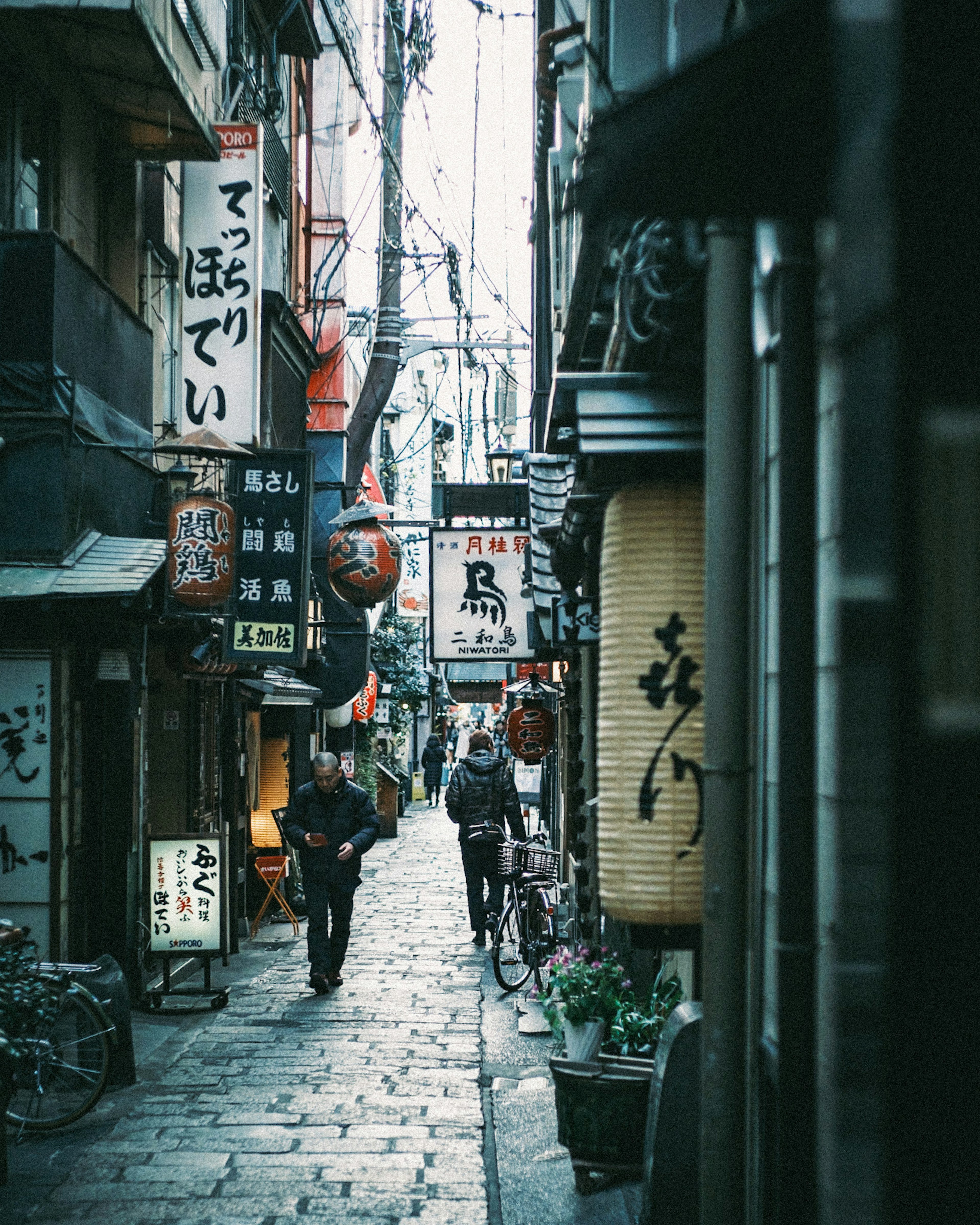 Narrow alley lined with restaurant signs and lanterns