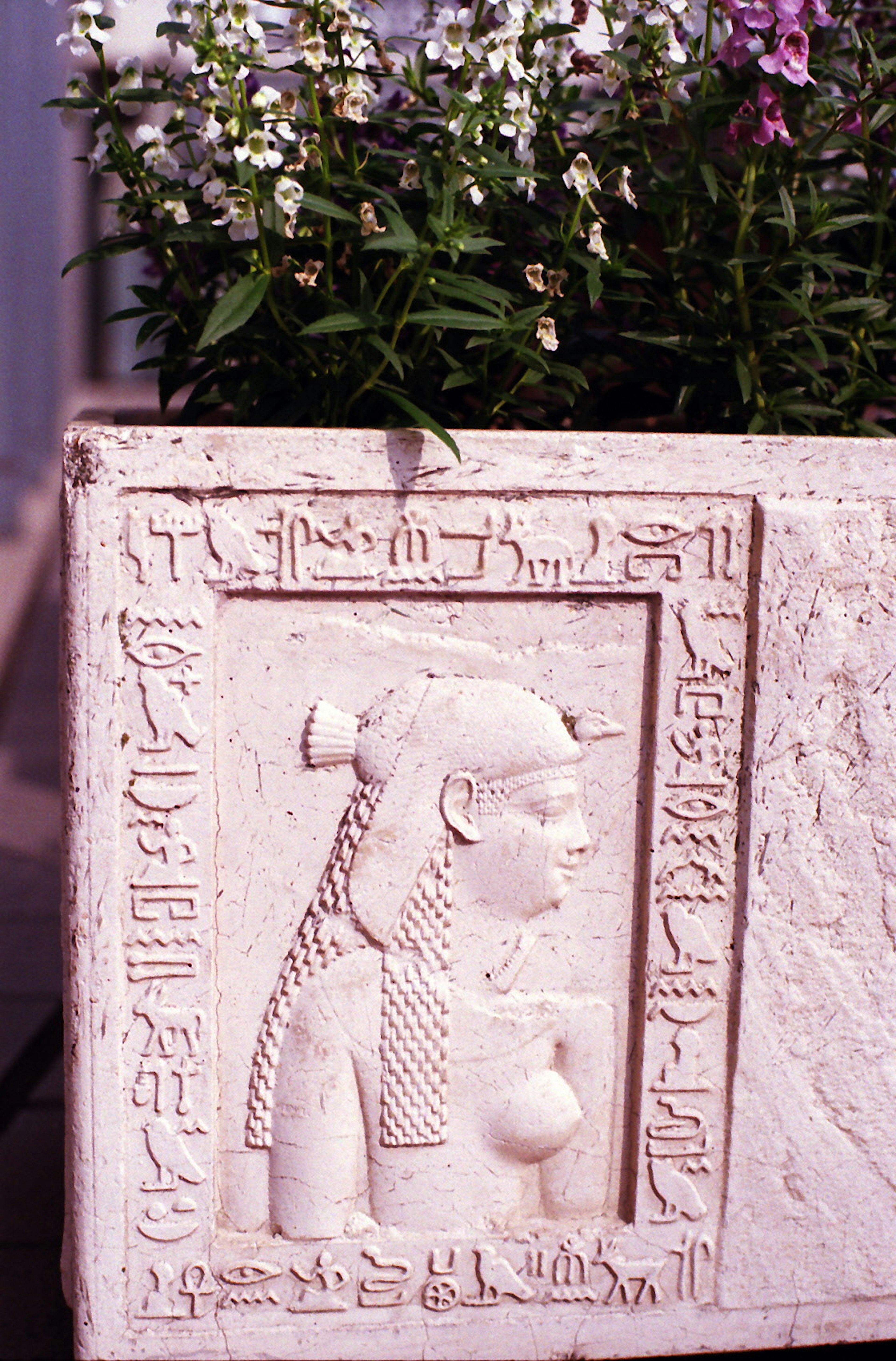 Carved female figure with hieroglyphs on a white stone planter