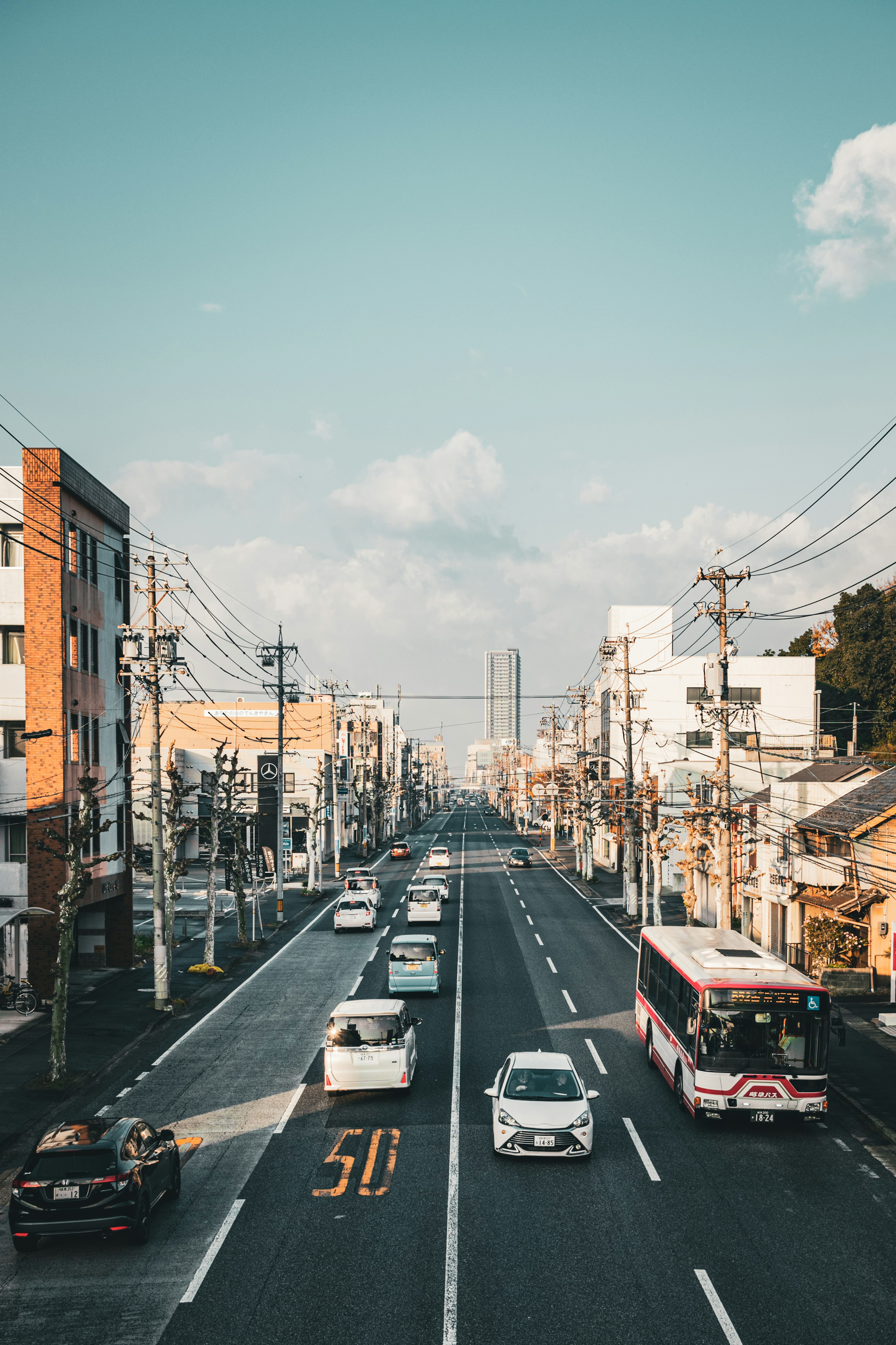 青空の下に延びる都市の道路に車が走っている風景