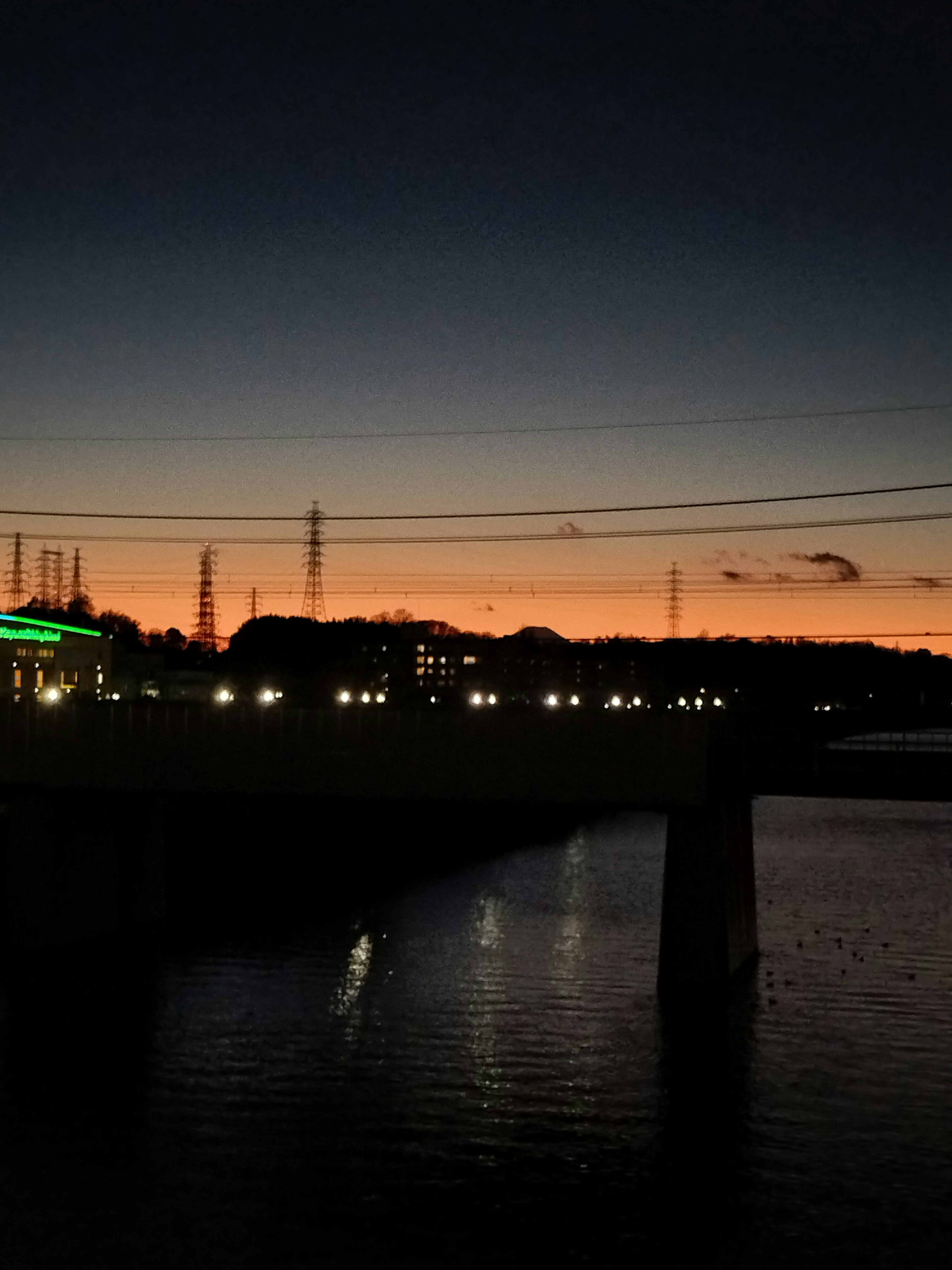 夕暮れ時の橋と川の風景で、街の明かりが反射している