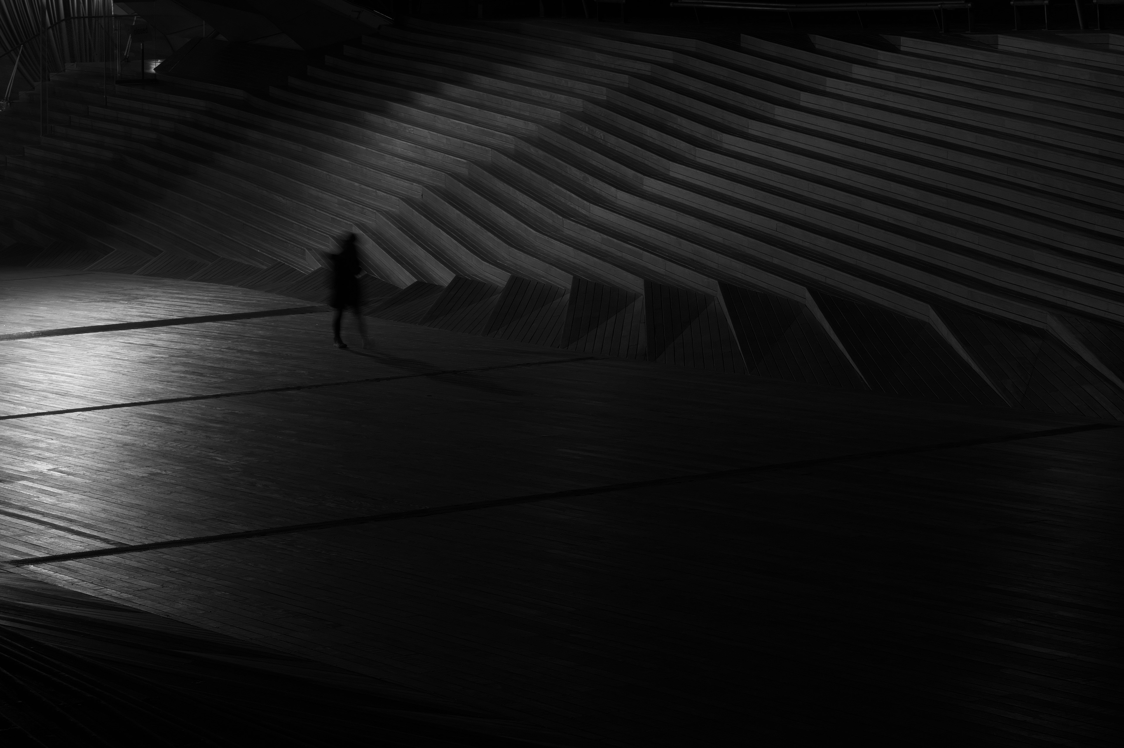 Silhouette of a person walking on geometric stairs in a dark setting