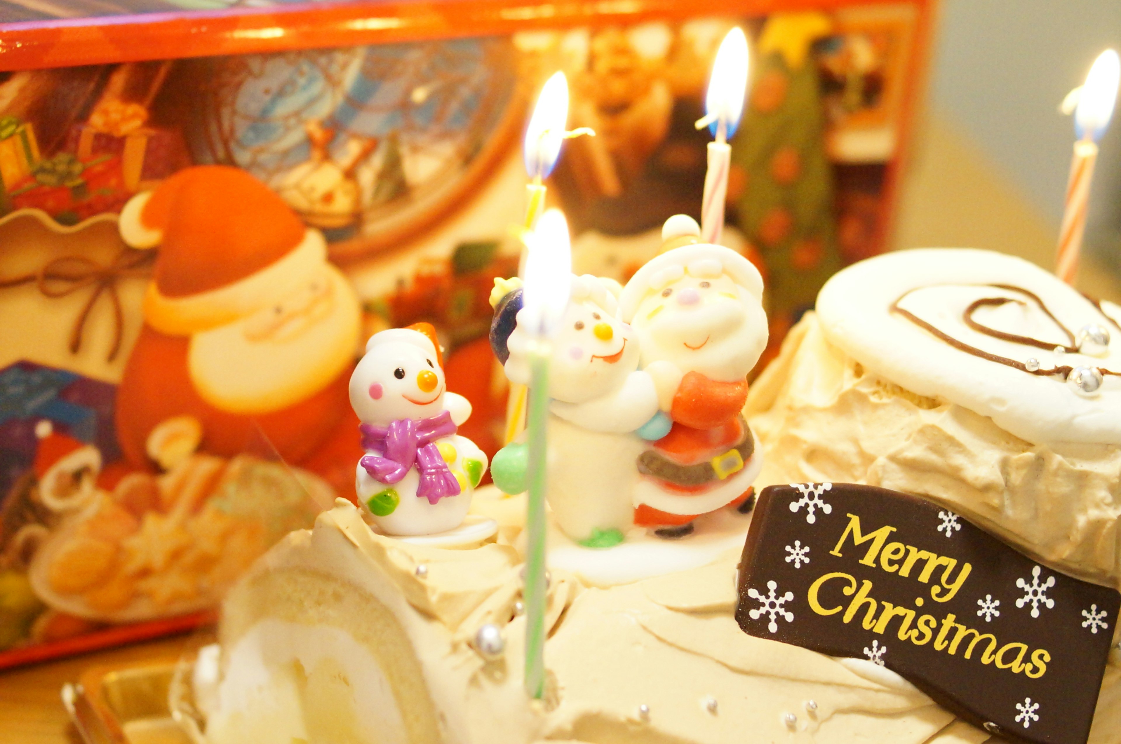 Torta di Natale decorata con figurine di Babbo Natale e pupazzo di neve candele e un cartello Buon Natale