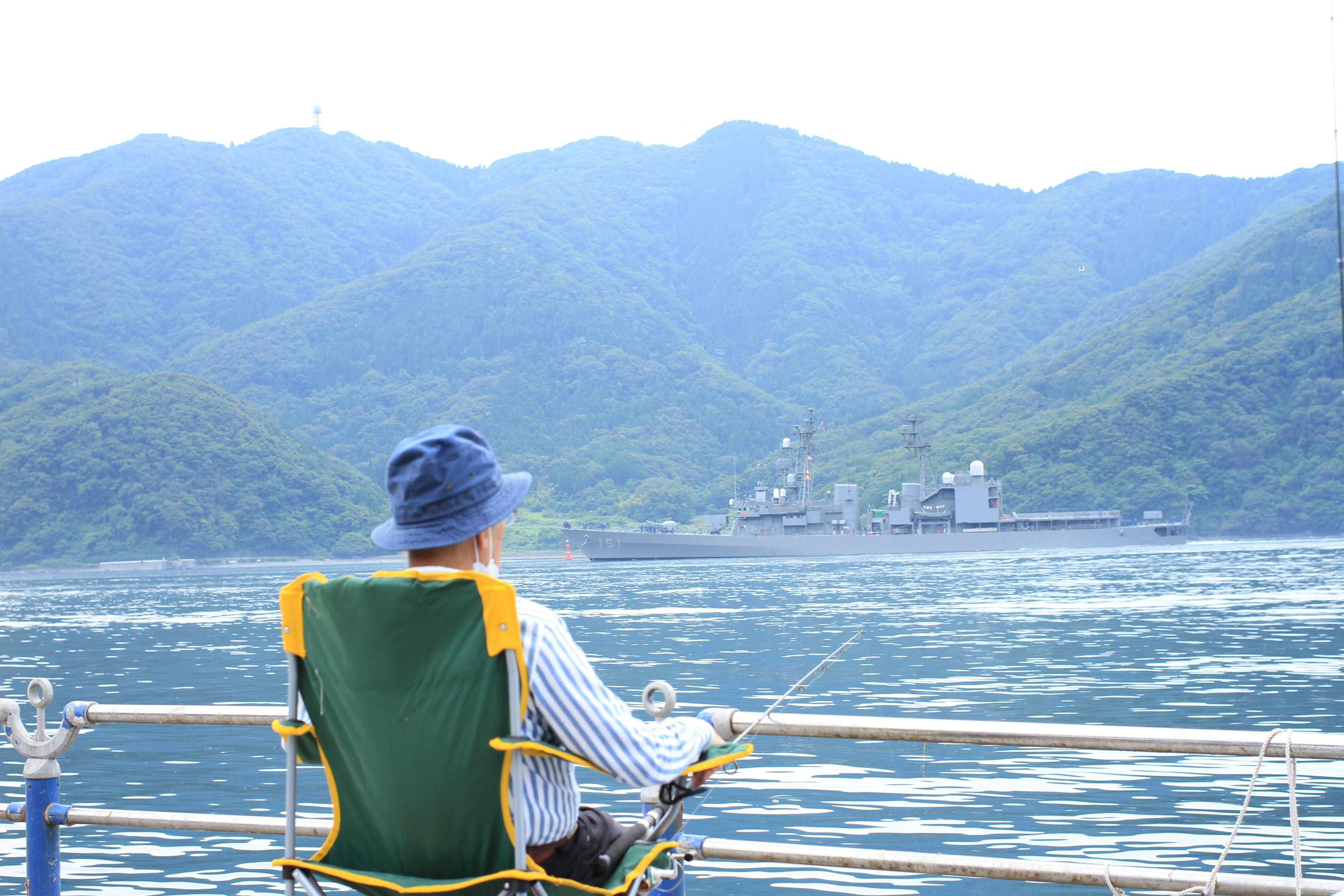 Man sitting in a chair by the sea with mountains in the background