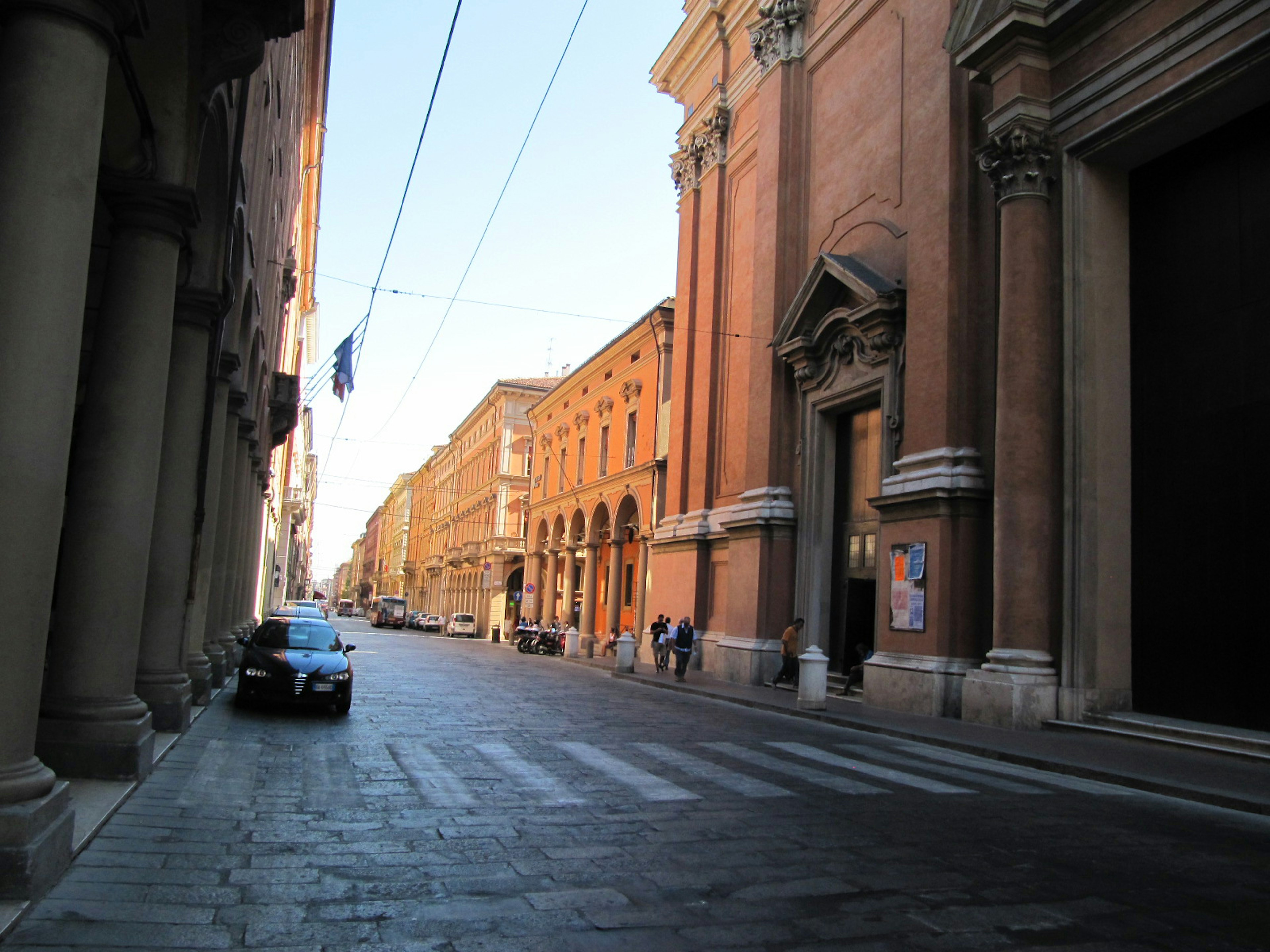 Vista di una strada tranquilla a Bologna con vecchi edifici e cielo blu chiaro