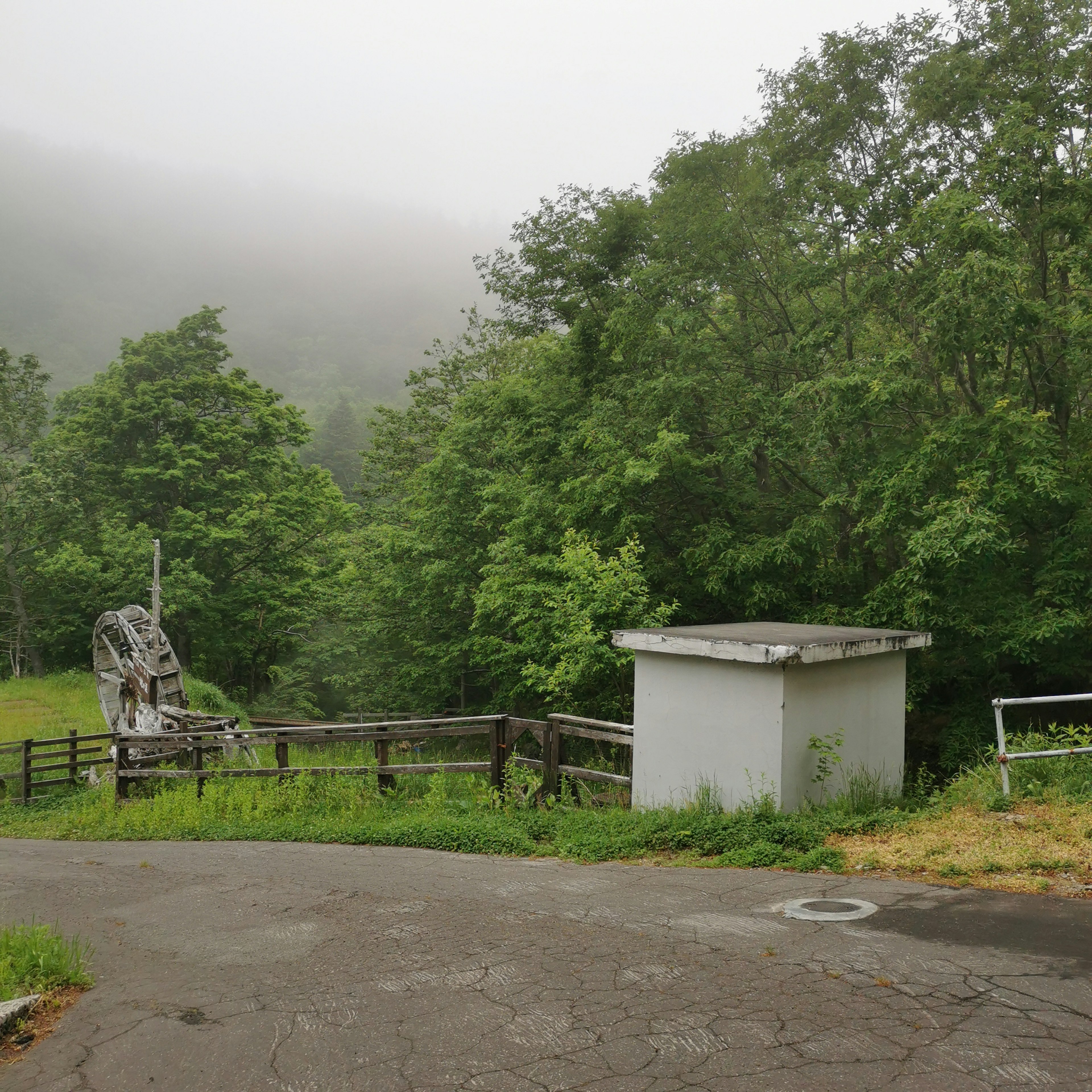 A white structure and an old device surrounded by trees in a quiet area