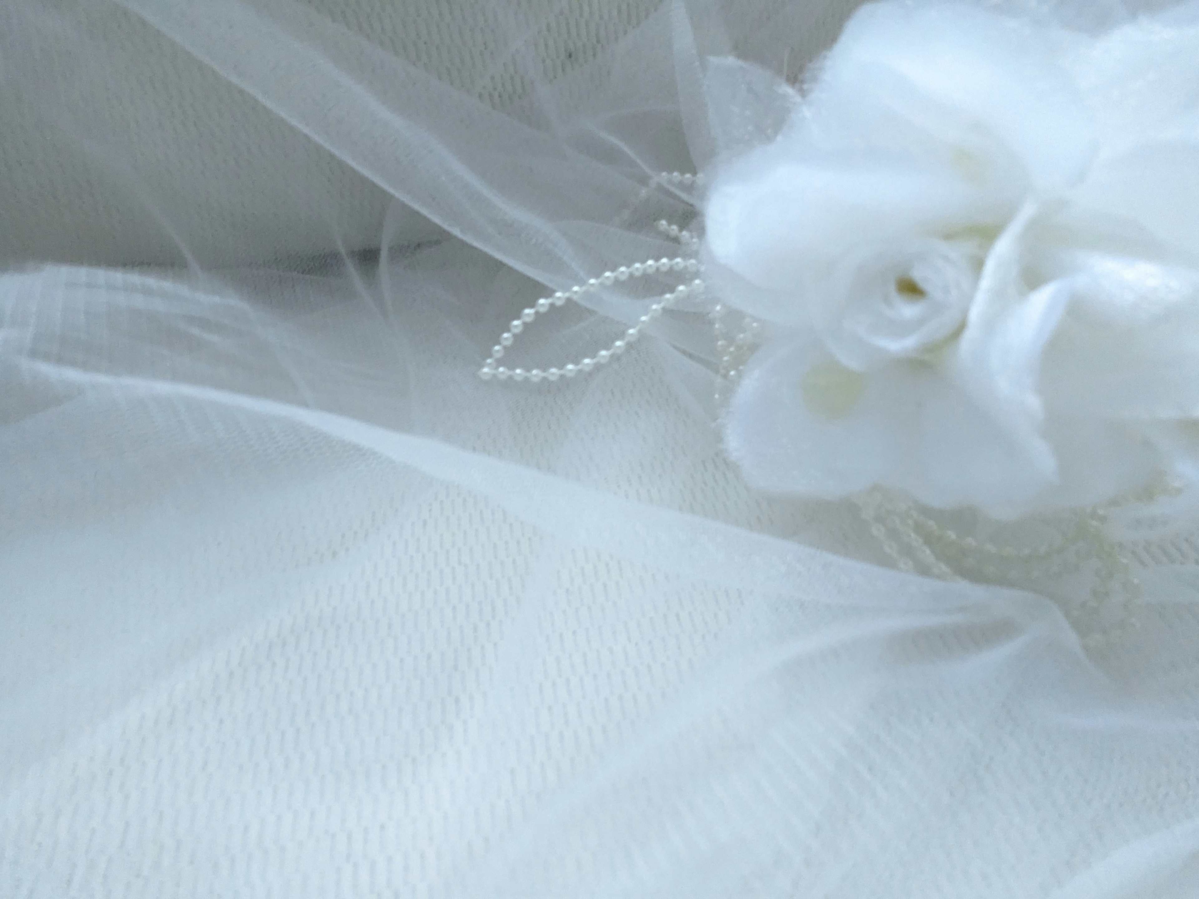 Soft tulle fabric featuring a white flower and pearl accents