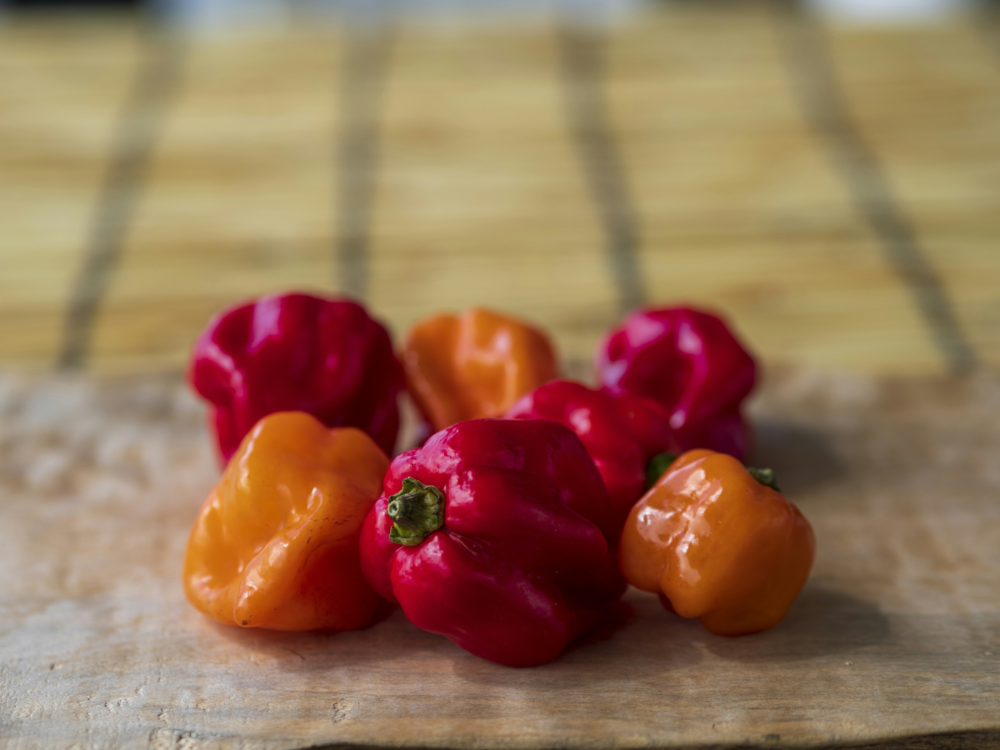 Red and orange habanero peppers arranged on a wooden board