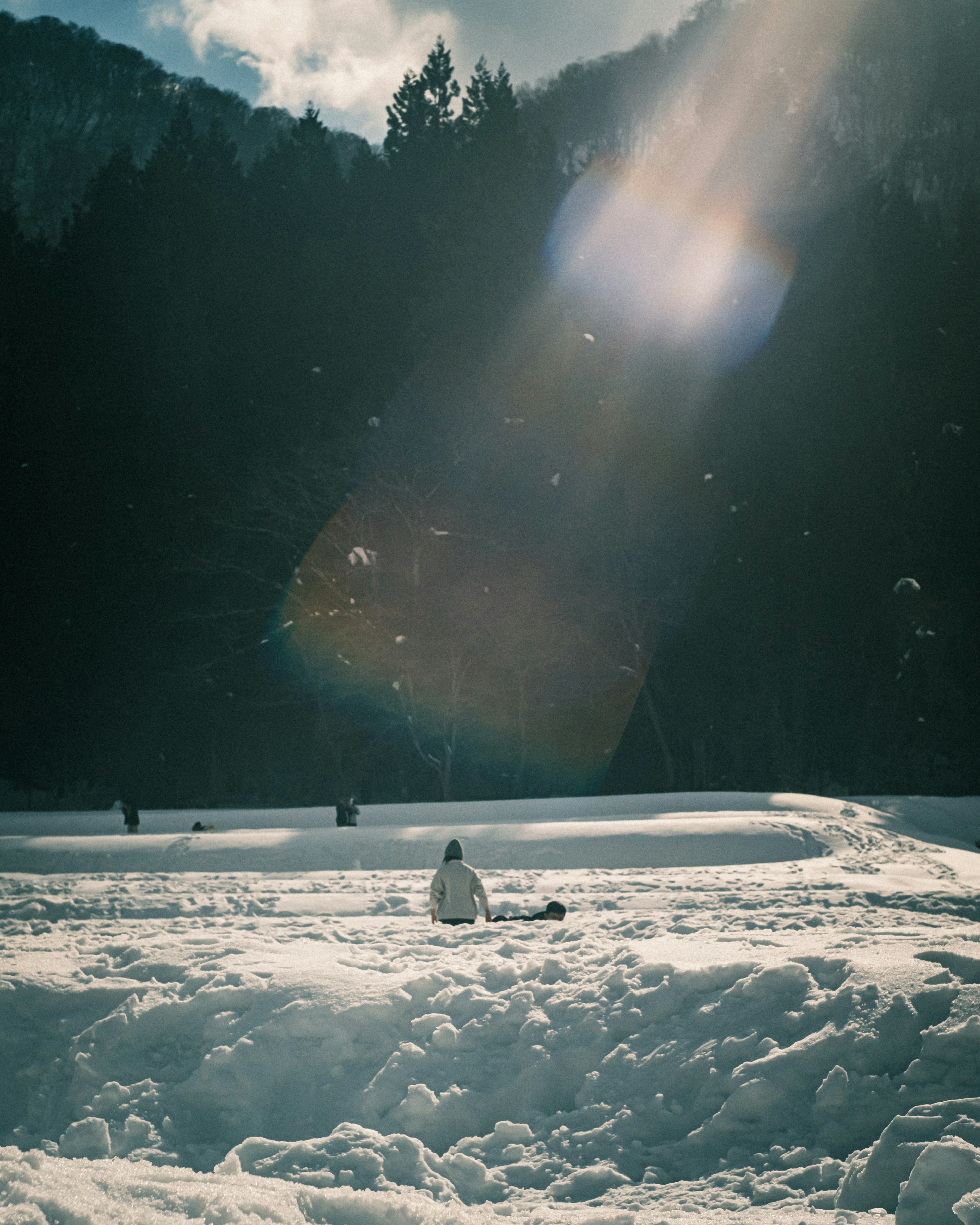 A person sitting in the snow with rays of light shining down