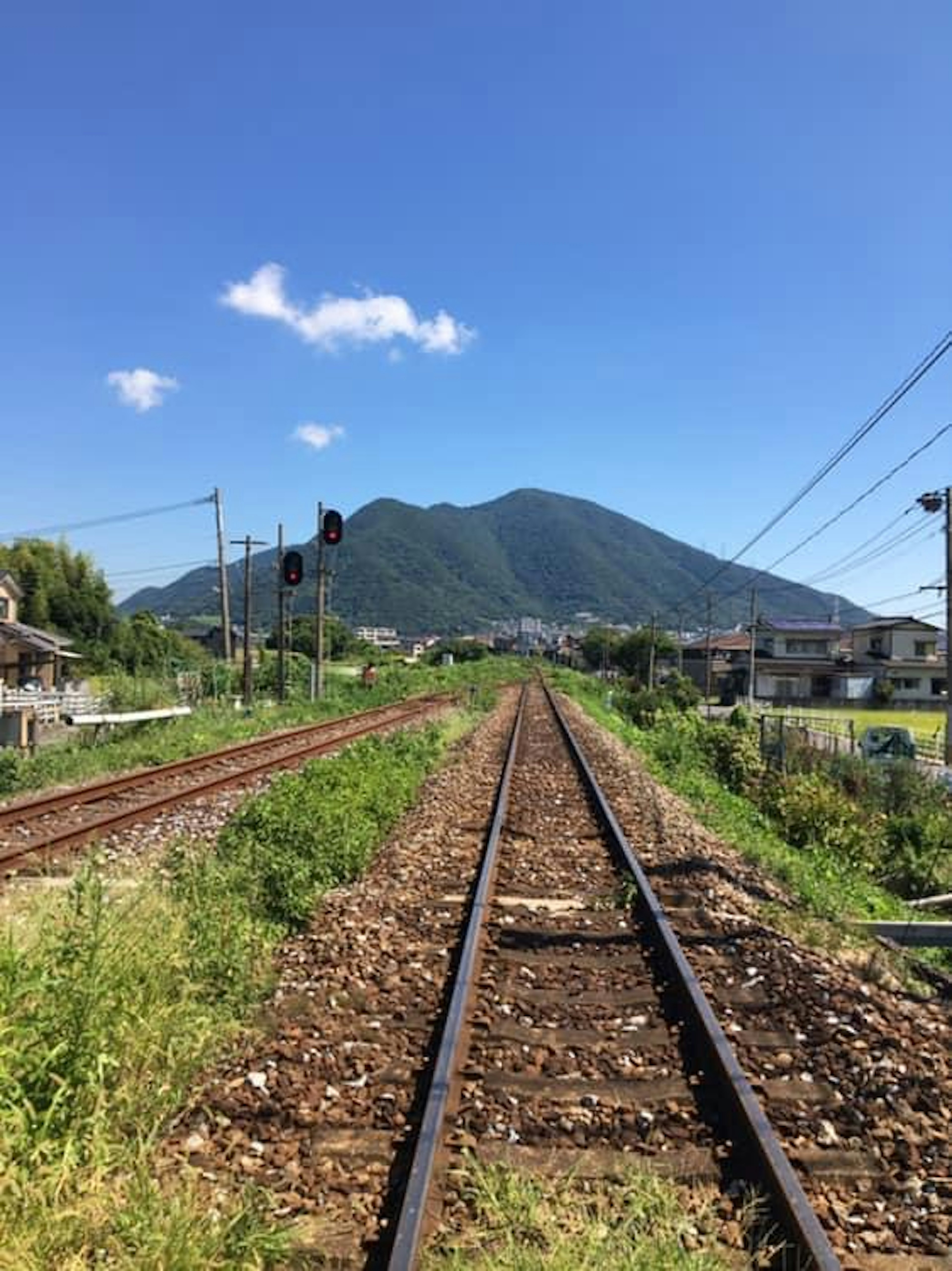 View of railway tracks leading to a mountain under a clear blue sky