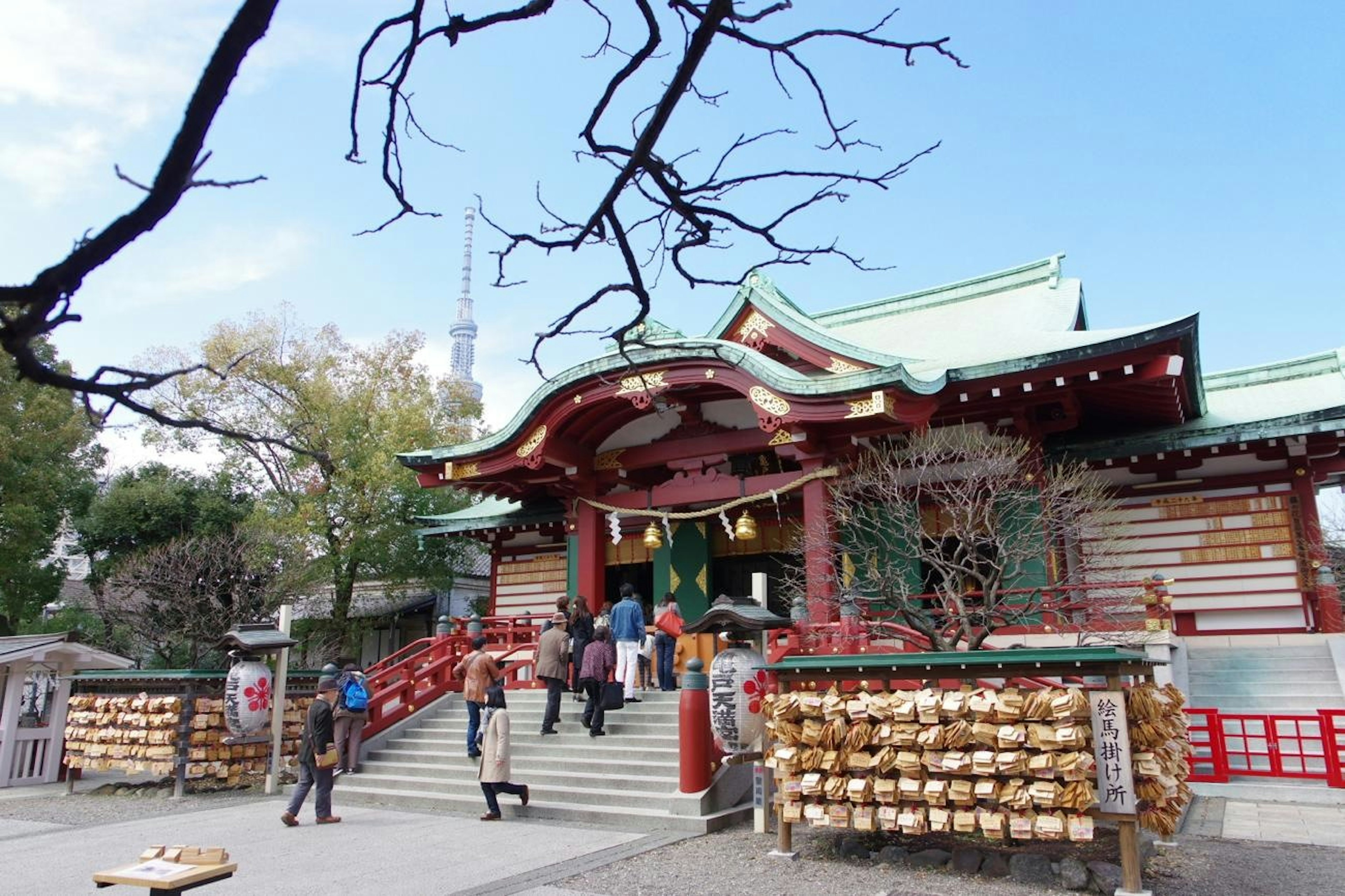 神社の赤い屋根と階段に人々が集まる風景