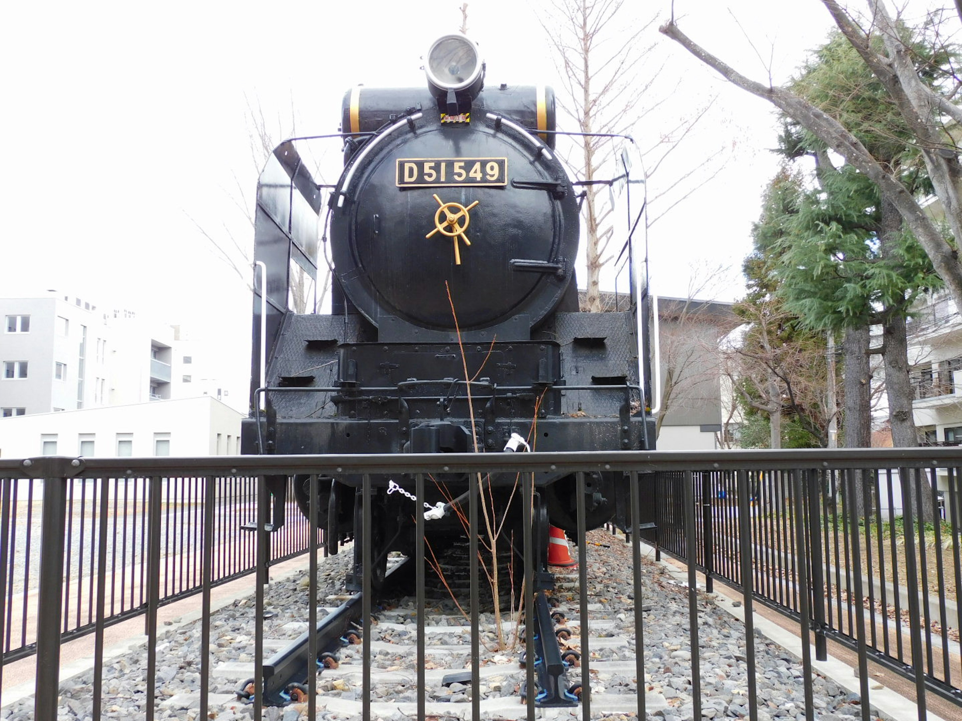 Una locomotora de vapor negra colocada sobre rieles con un número visible en la parte delantera