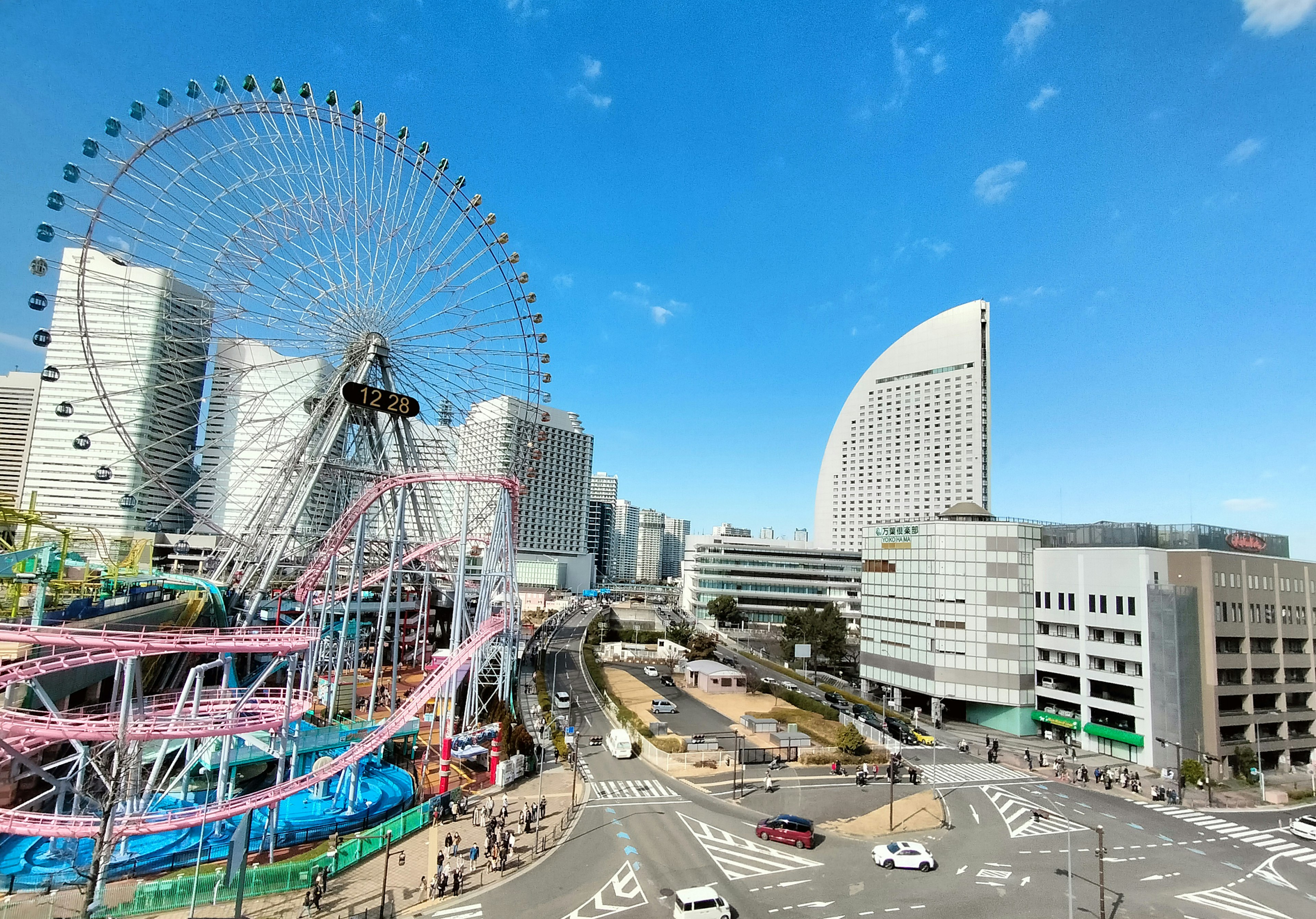 Paisaje urbano de Yokohama con una noria y edificios modernos bajo un cielo azul claro