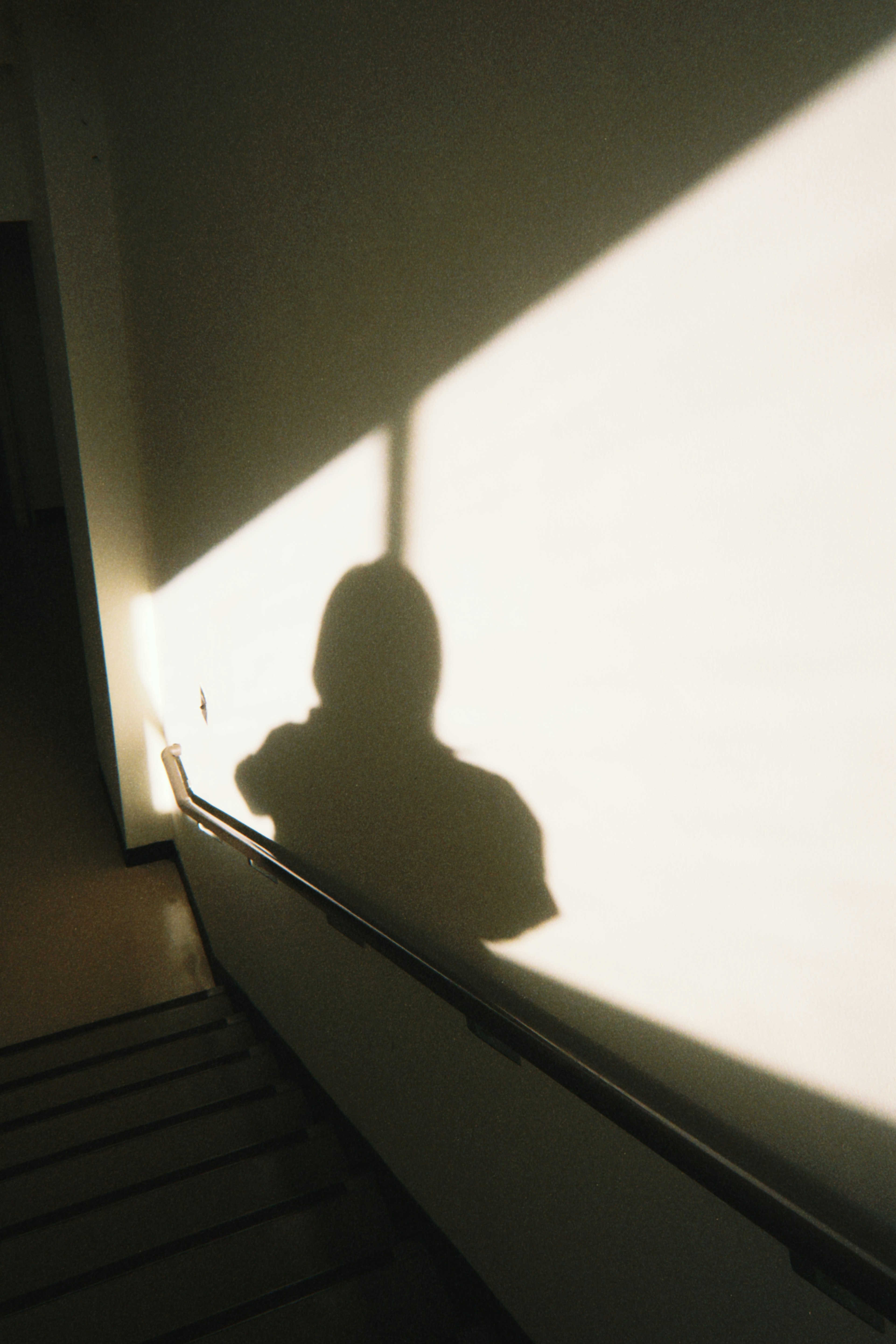 Sombra de una persona en la pared de una escalera con contraste de luz