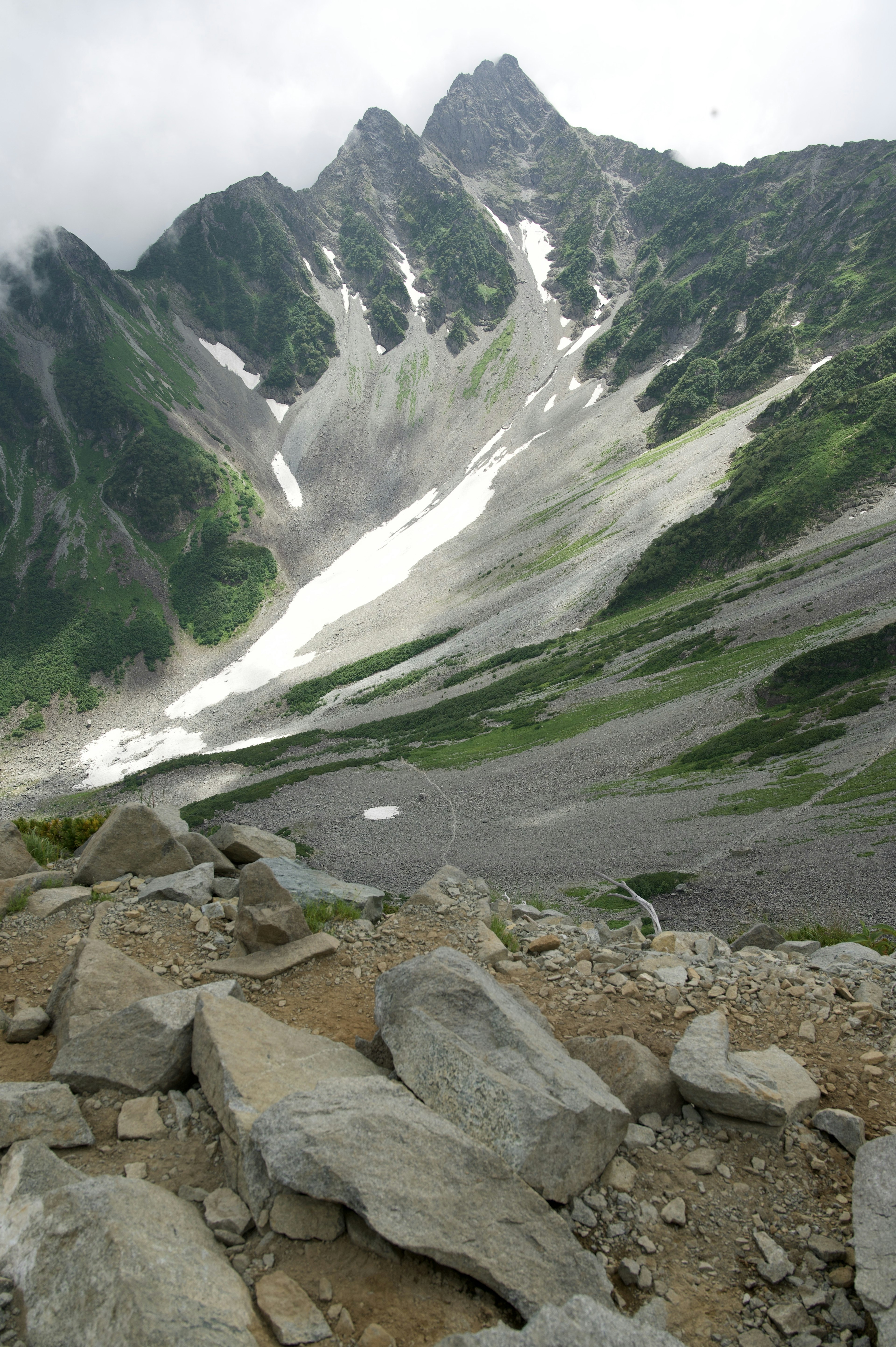 美しい山の風景、雪のある峰と緑の斜面、岩の道