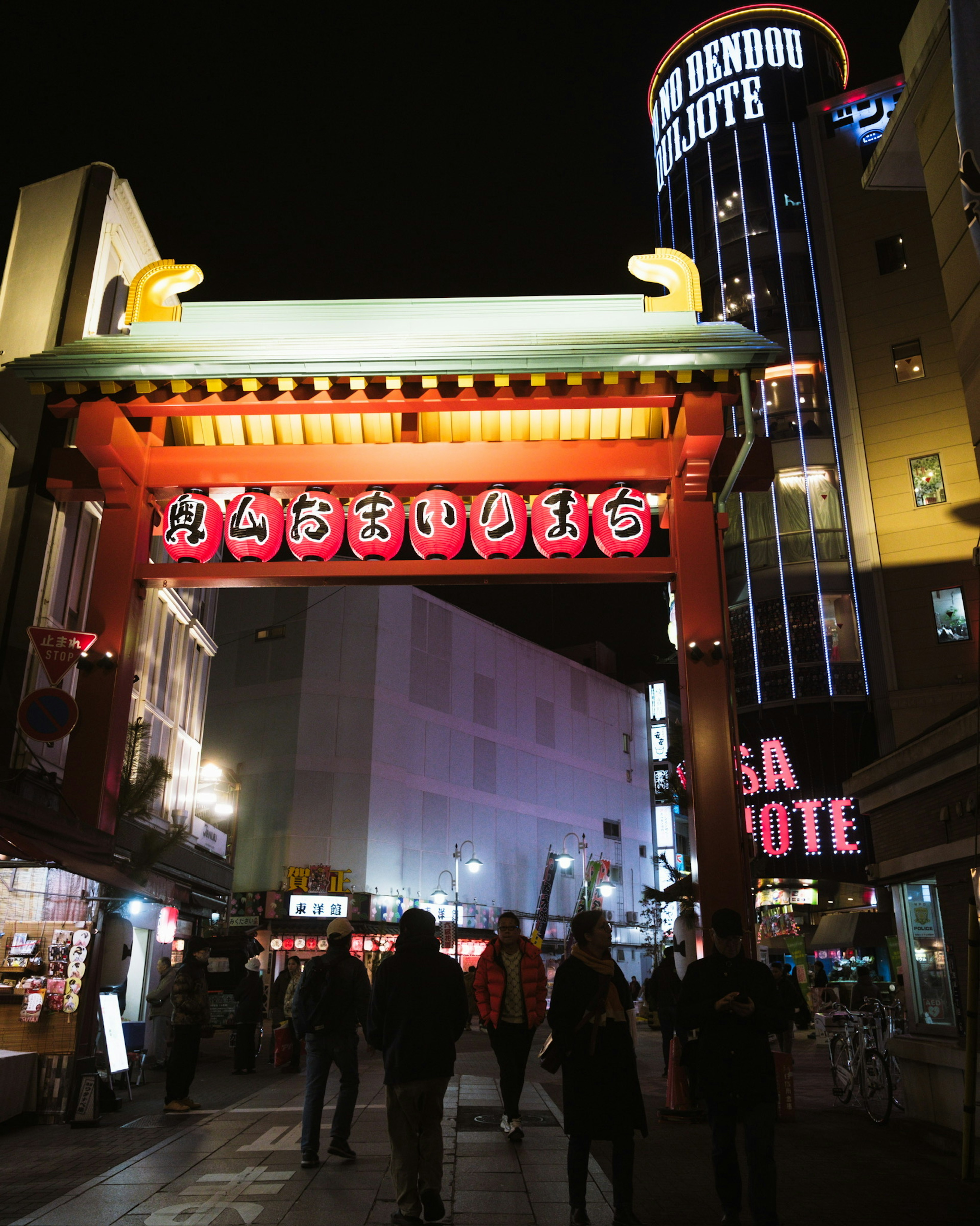 Red lantern archway illuminated at night with people walking underneath