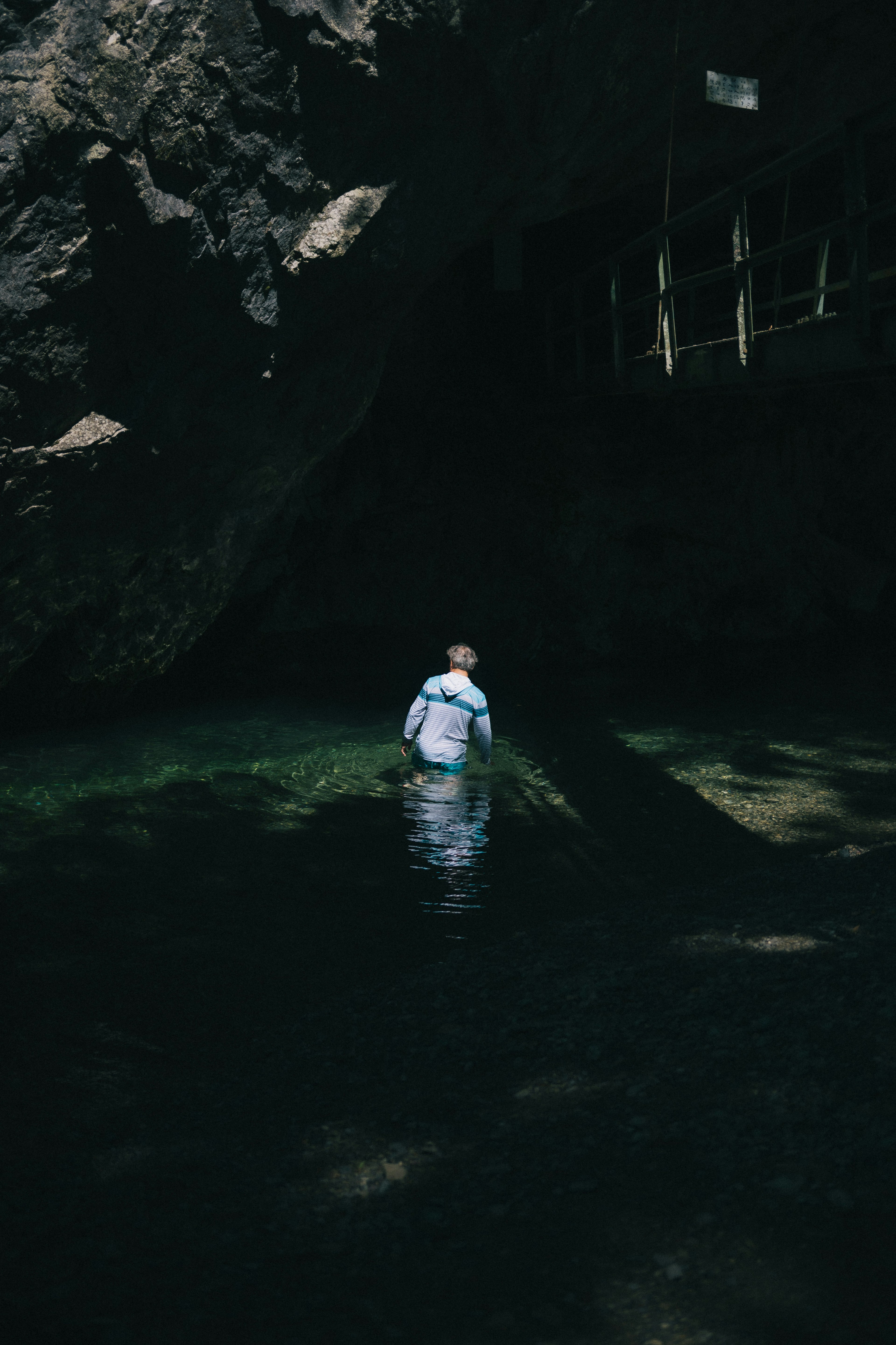 Person standing in water facing away with rocky surroundings