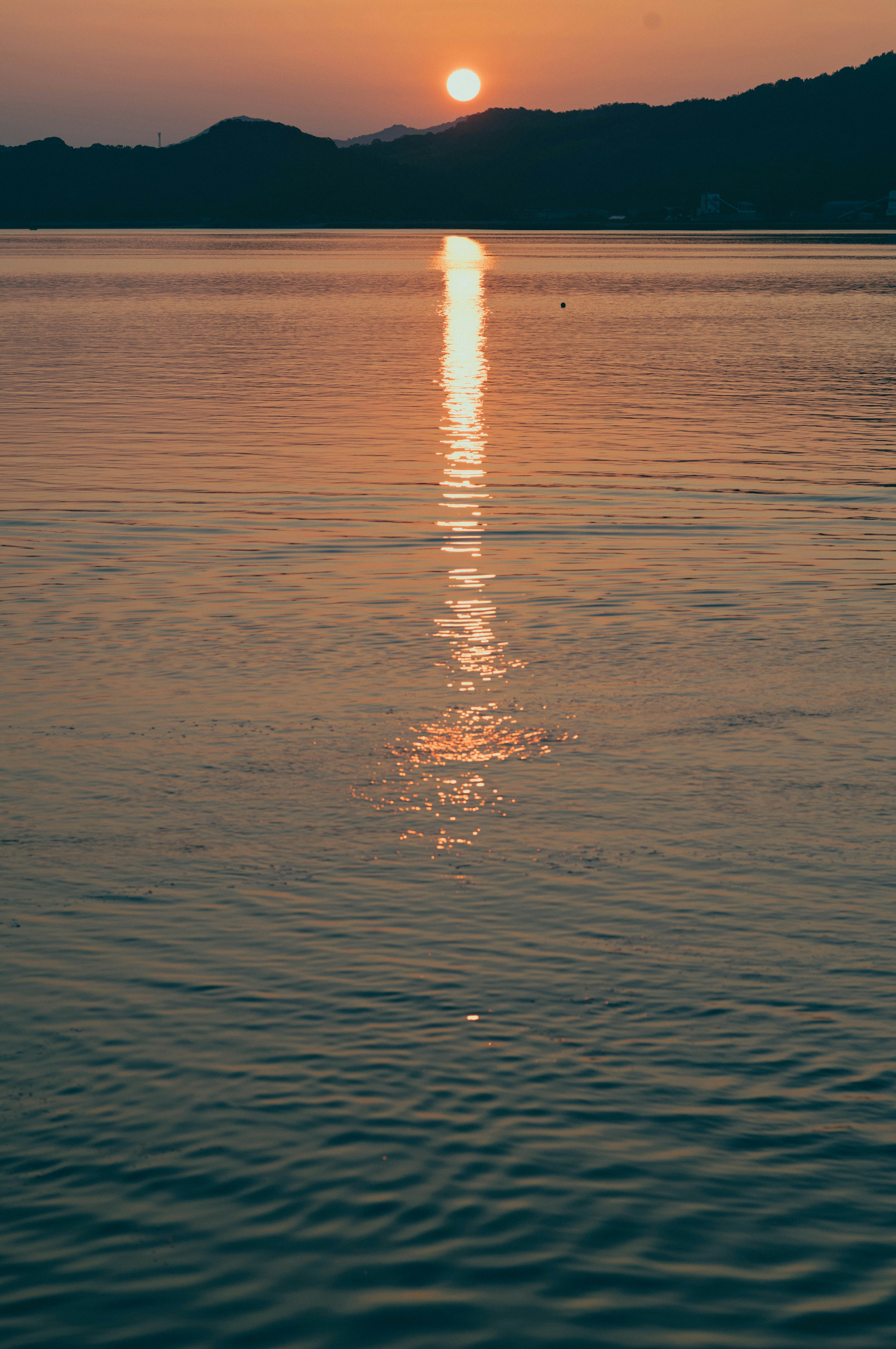 Calm water reflecting the sunset and silhouetted mountains