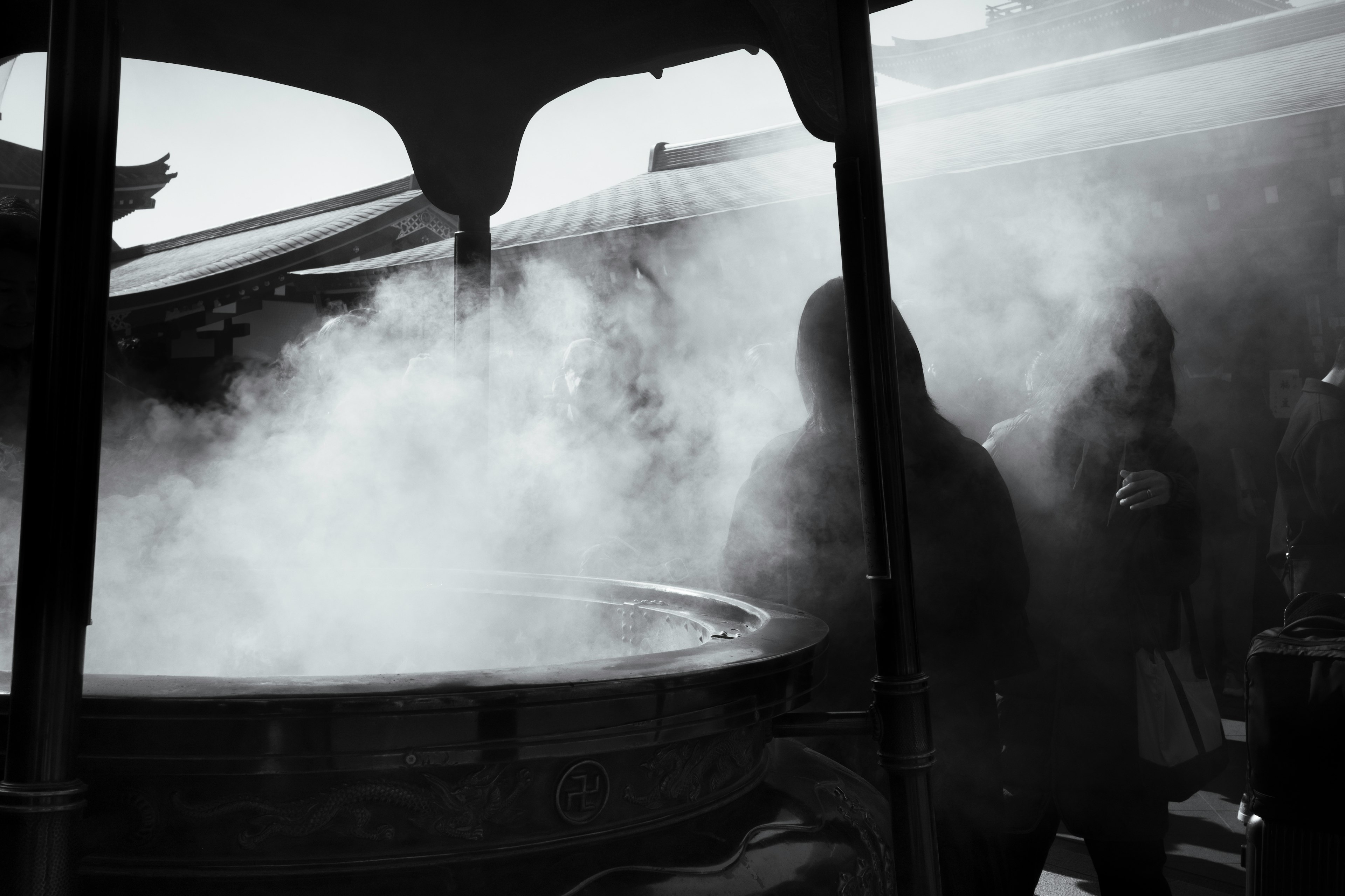 Silhouettes of people performing a ritual in a temple surrounded by smoke