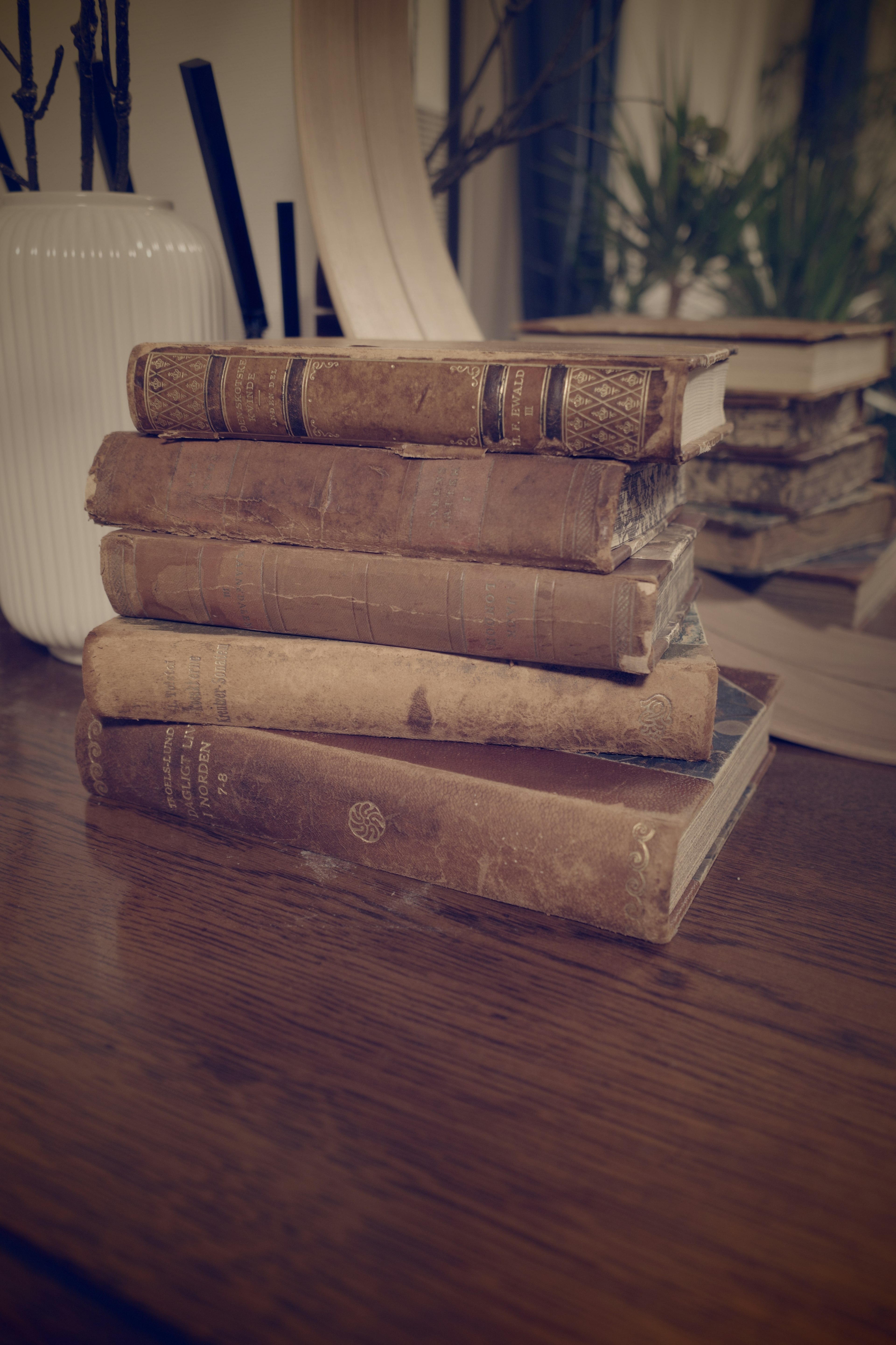 Une pile de vieux livres sur une table en bois dans une ambiance chaleureuse