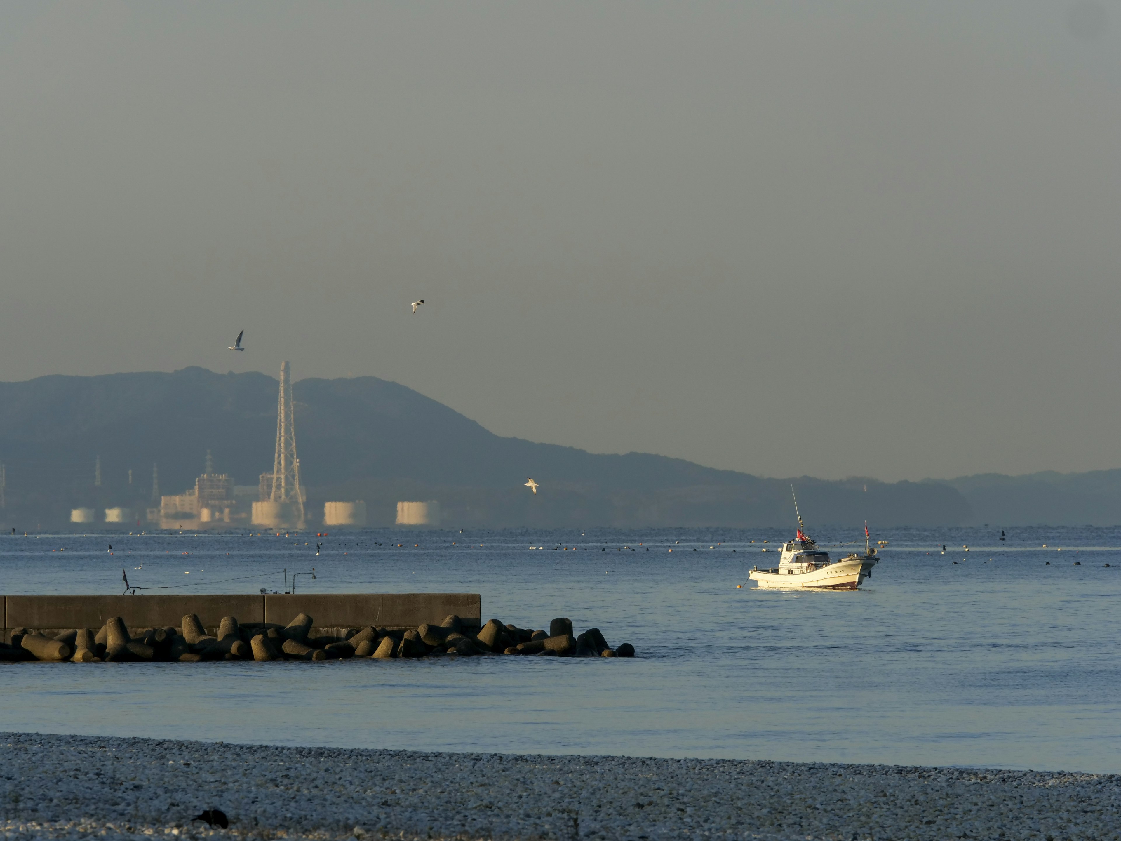 A small white fishing boat sailing on the sea with distant mountains