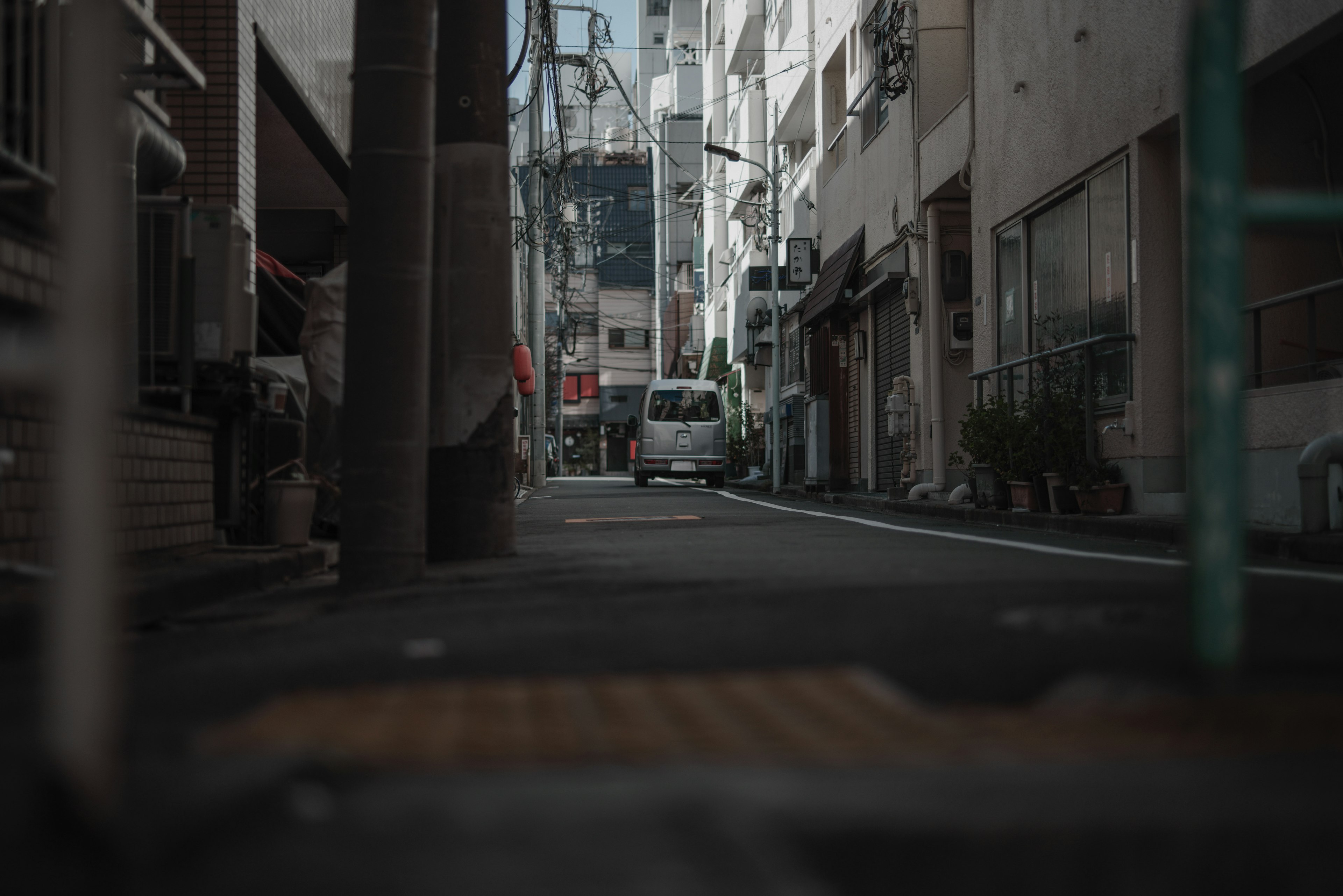 狭い路地に停車した車と周囲の建物が並ぶ様子