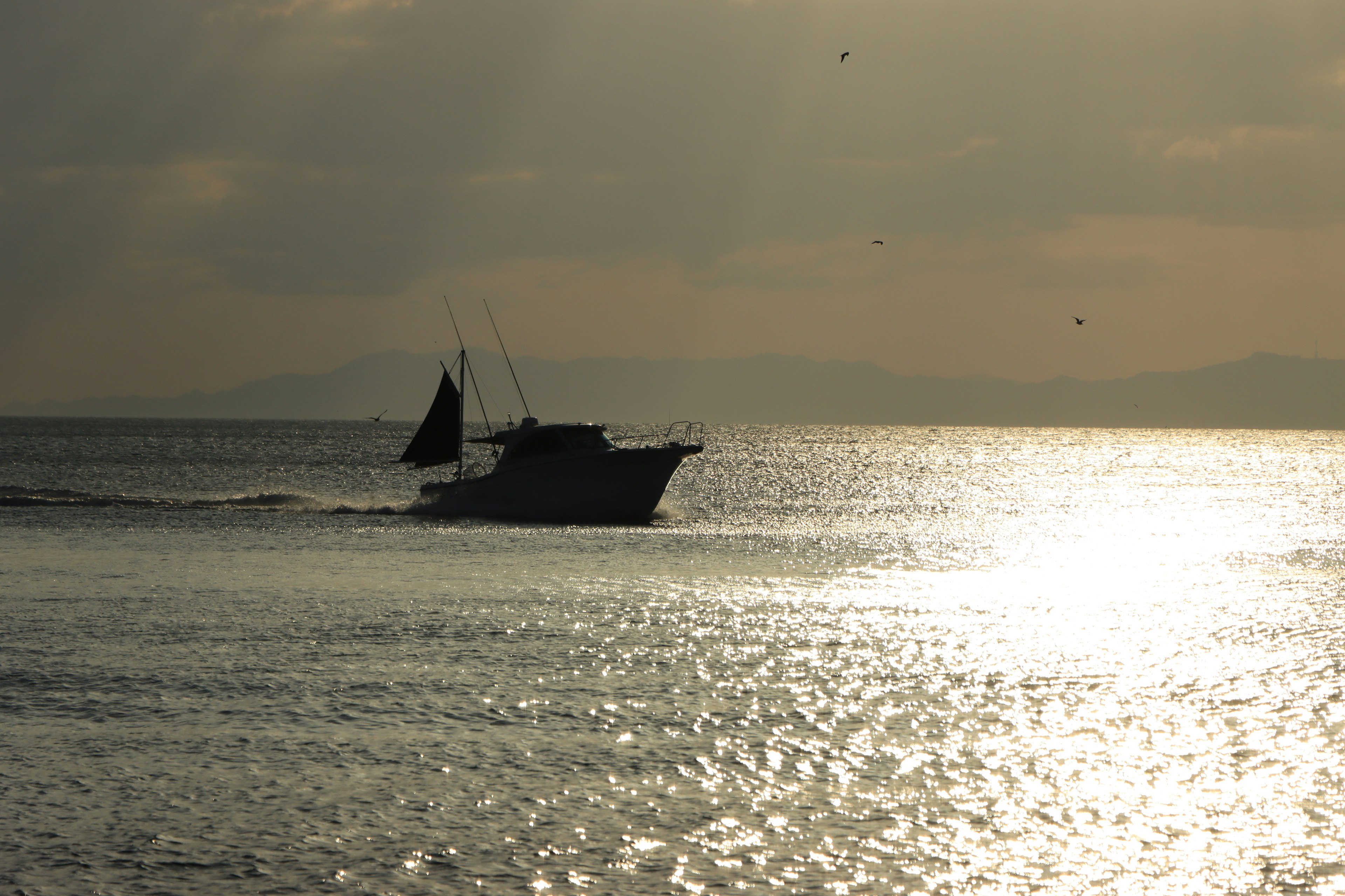 Silhouette di un peschereccio che naviga su un mare calmo con belle riflessioni