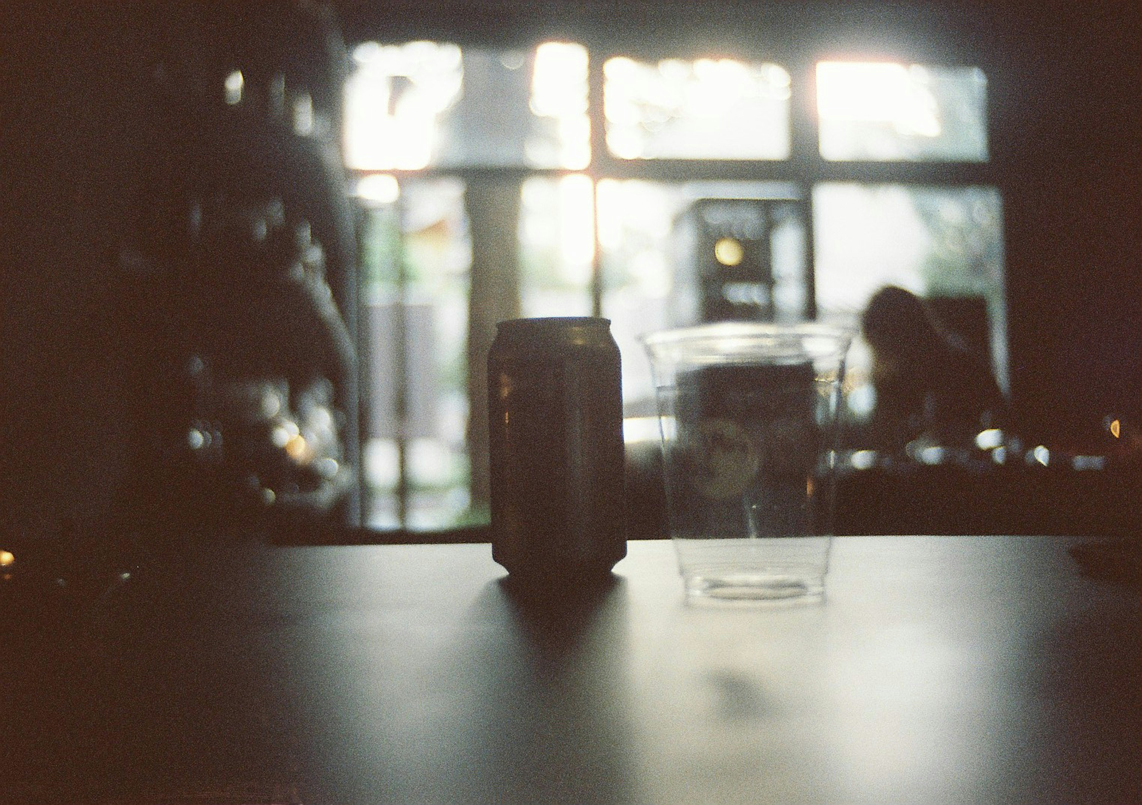 A can and a plastic cup on a table with natural light coming through the window in the background