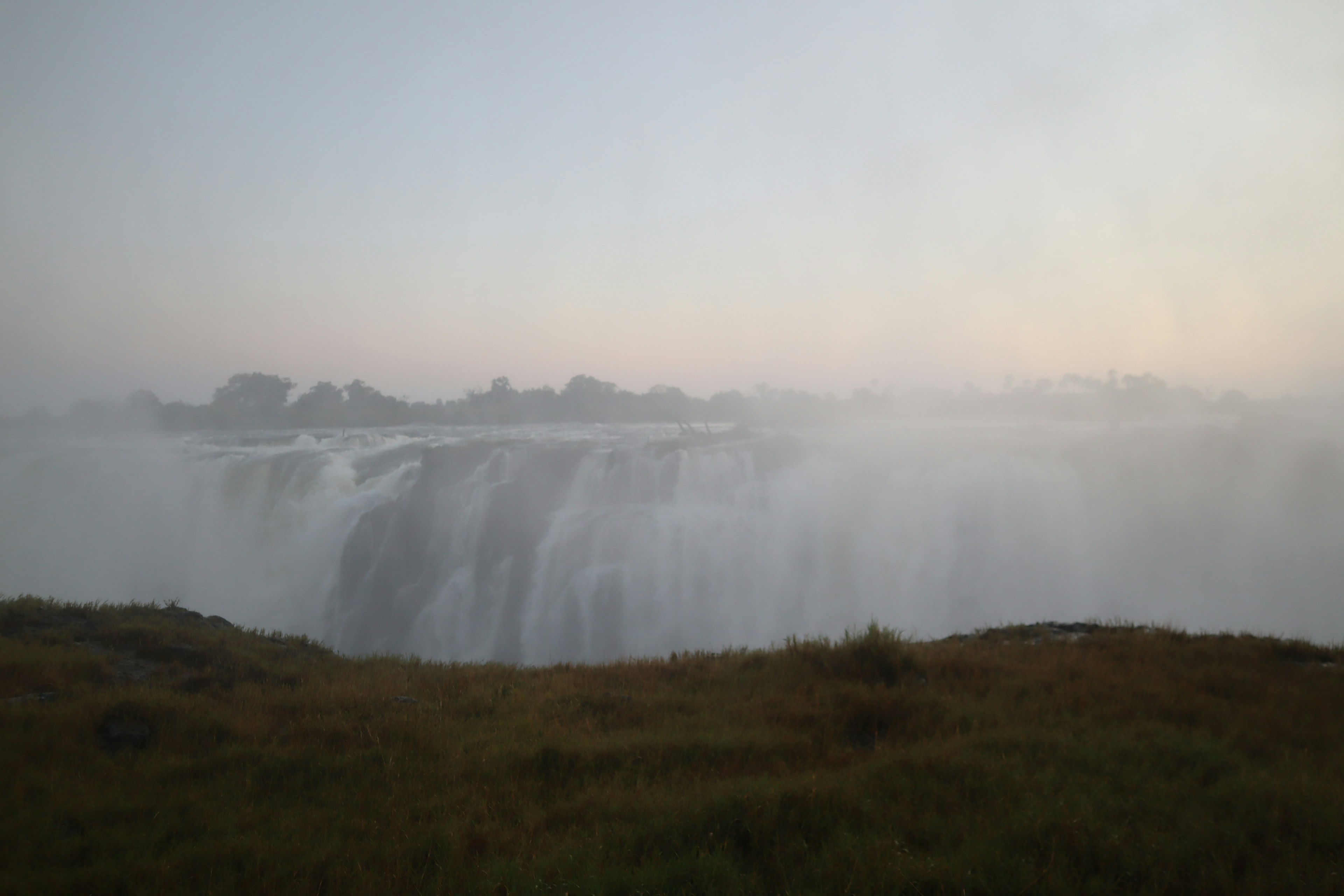 Misty view of a waterfall with surrounding grassland