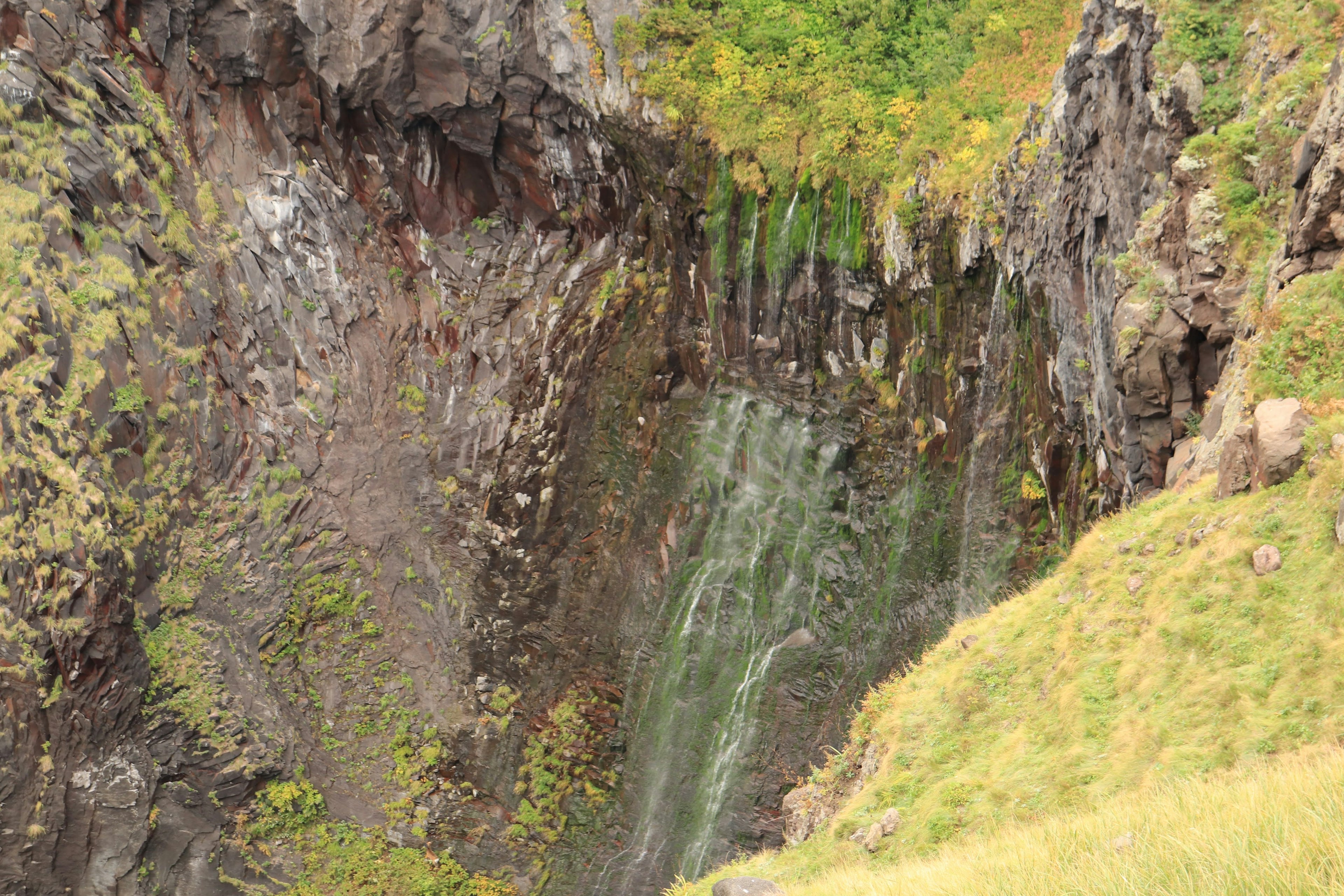 Una bellissima cascata che scende tra scogliere rocciose circondate da vegetazione lussureggiante