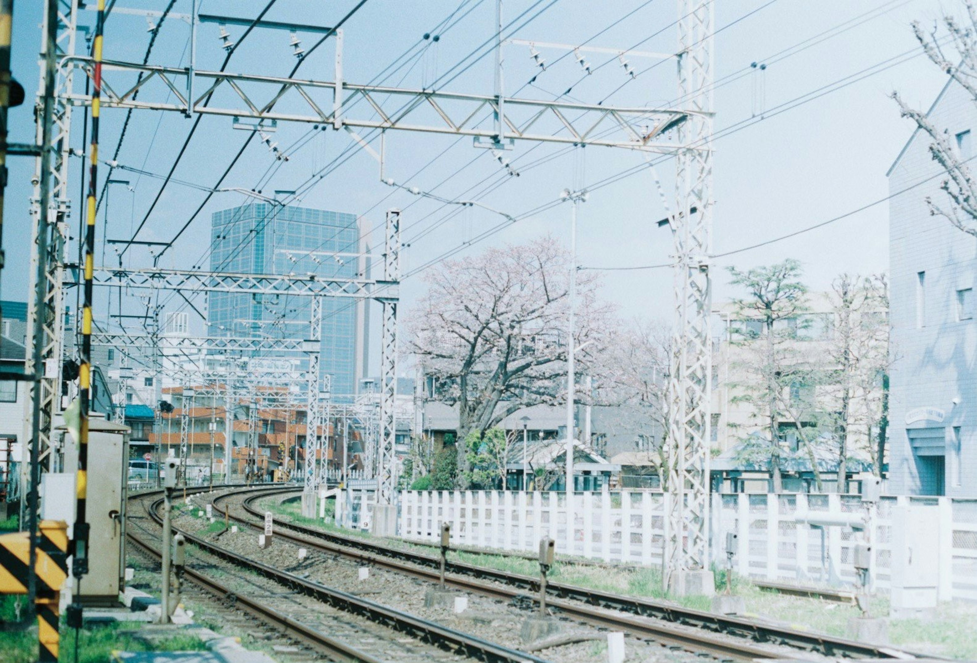 รางรถไฟโค้งพร้อมฉากหลังเป็นอาคารทันสมัยและต้นไม้