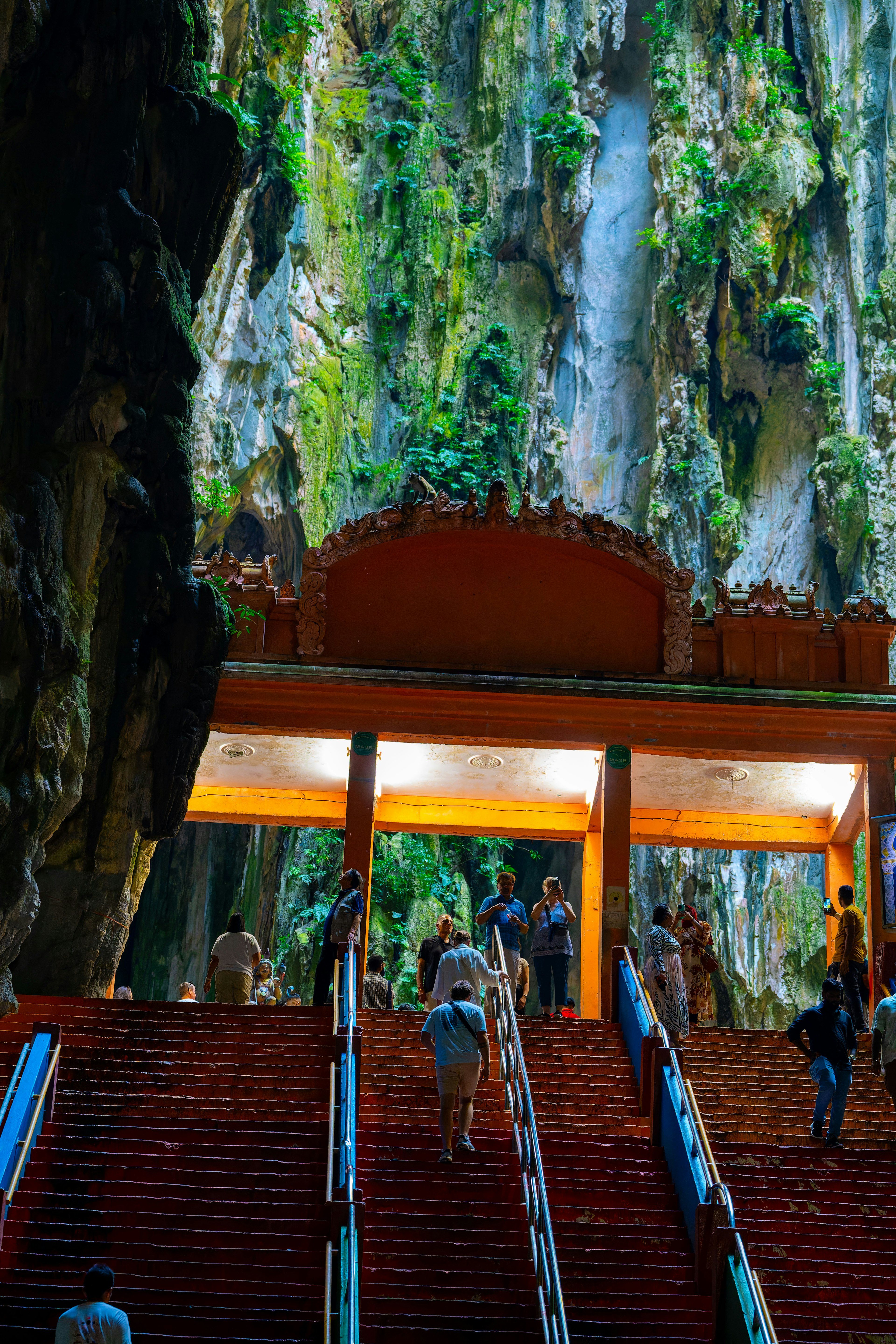 Vue des escaliers des grottes de Batu avec des murs rocheux verts en arrière-plan