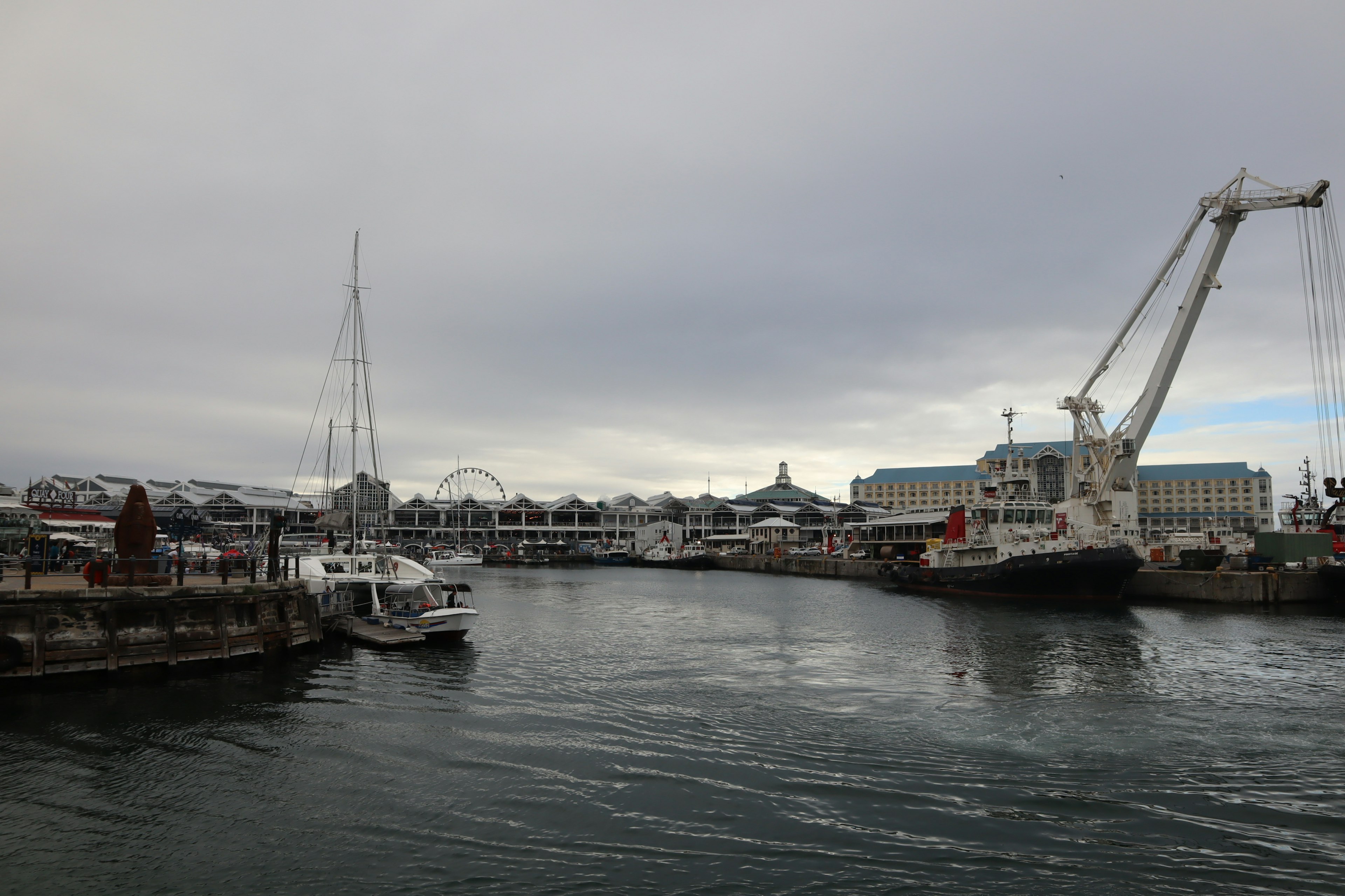 Blick auf einen Hafen mit festgemachten Booten und einem Kran