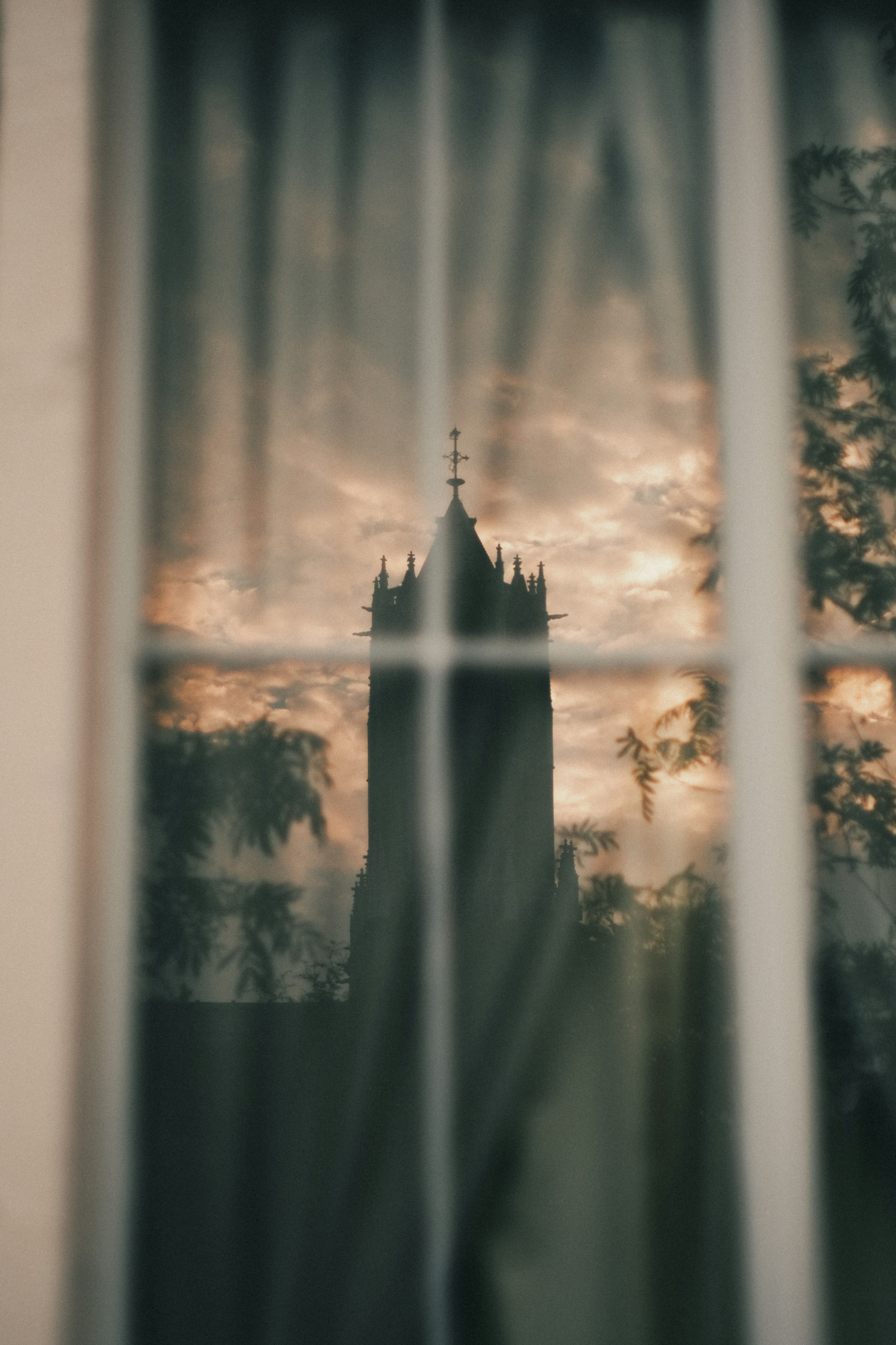 Silueta de una torre reflejada en una cortina con un cielo al atardecer