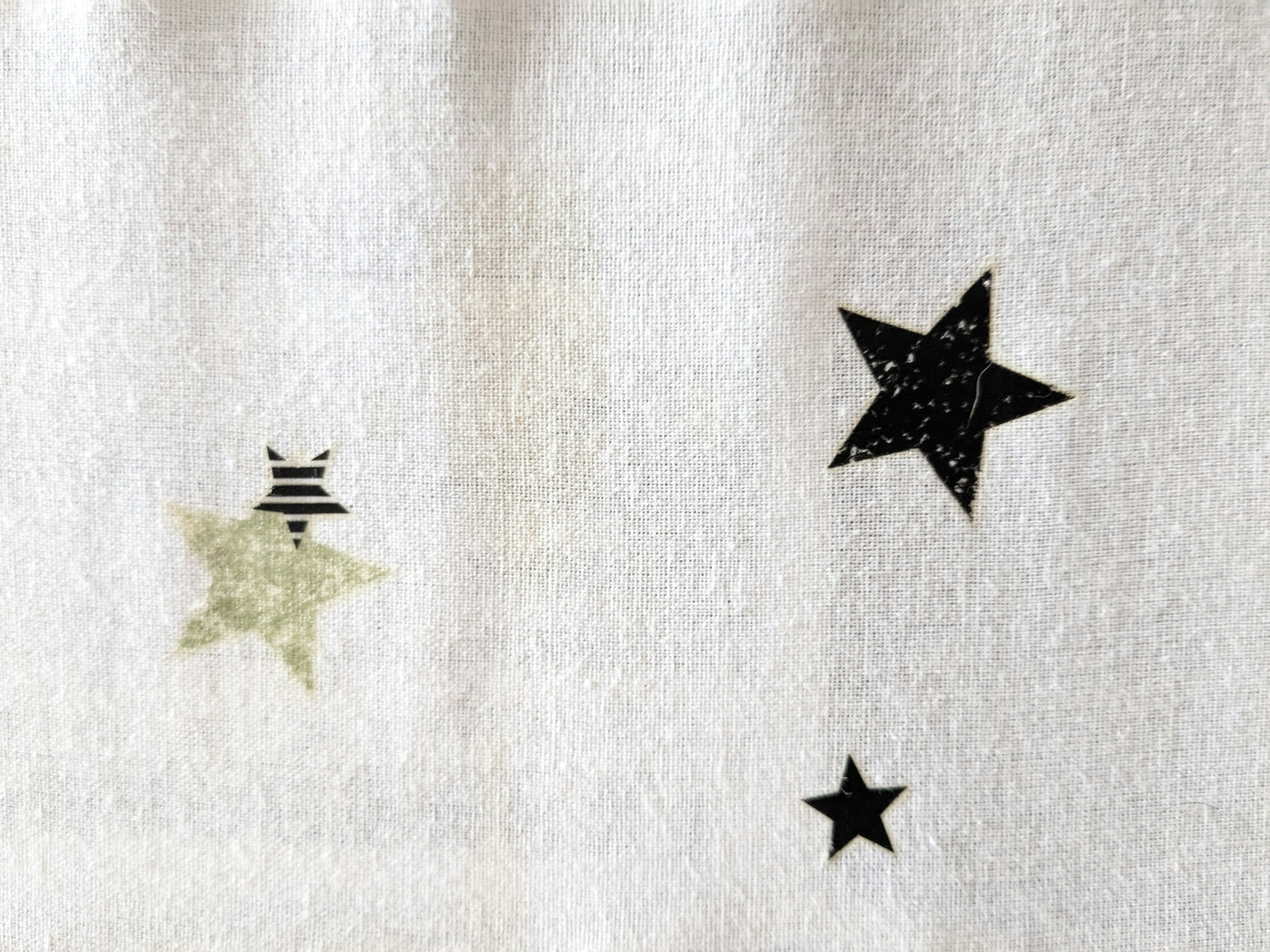 White fabric featuring black stars and one green star design