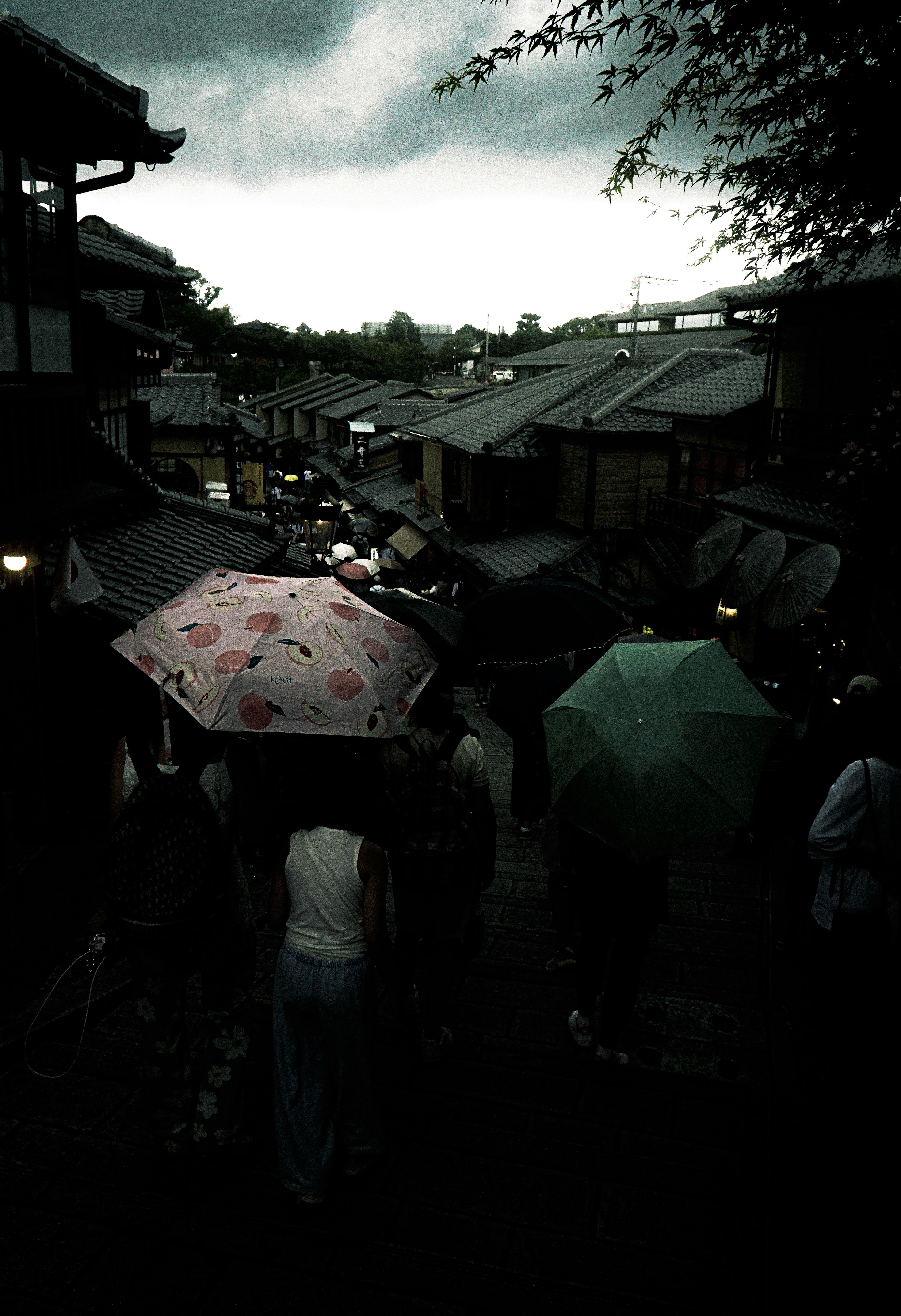 雨の中、傘を持った人々が古い町並みを歩く