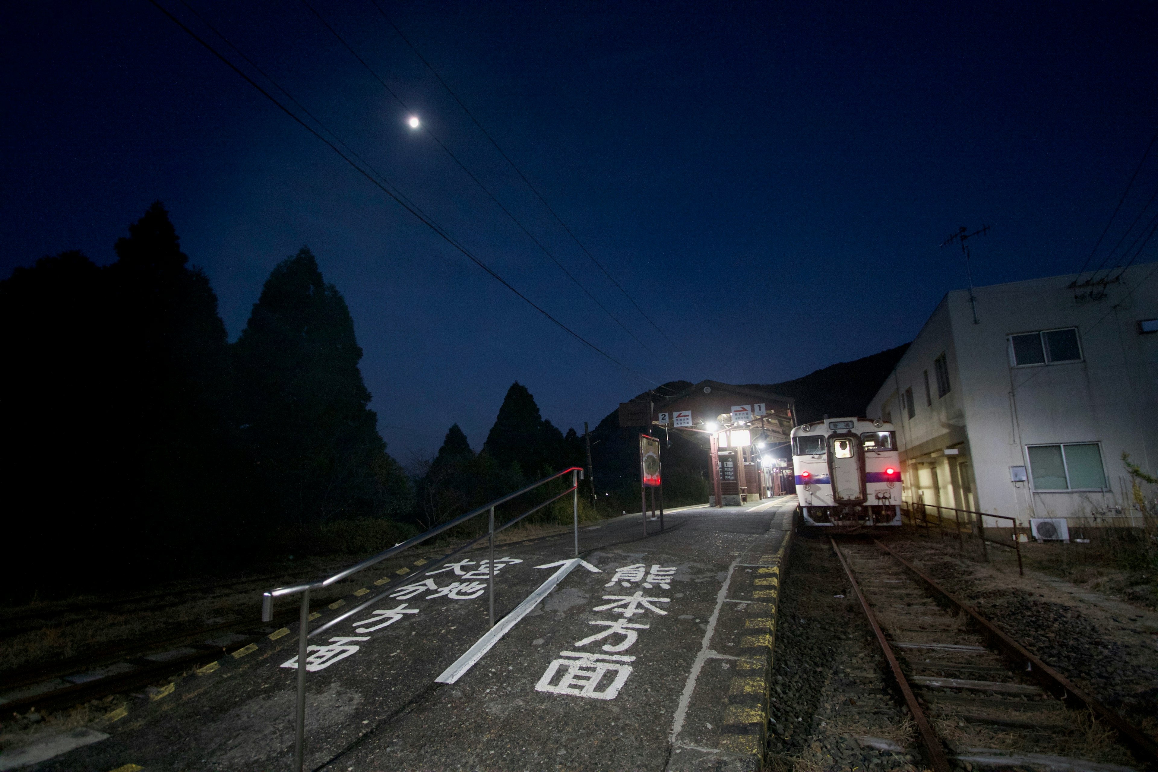 Treno in una stazione poco illuminata sotto la luna