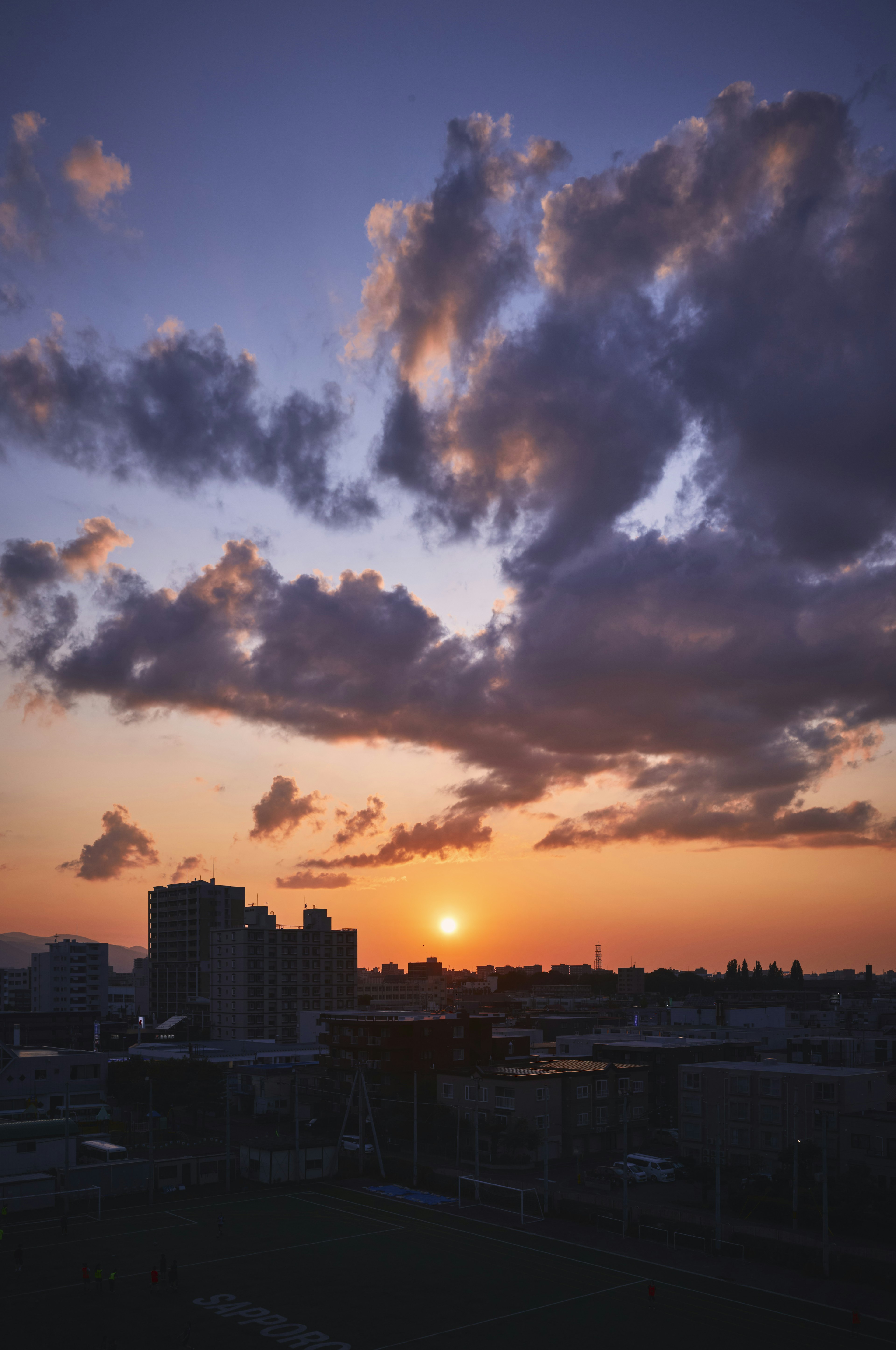 Stadtansicht bei Sonnenuntergang mit großen Wolken am Himmel