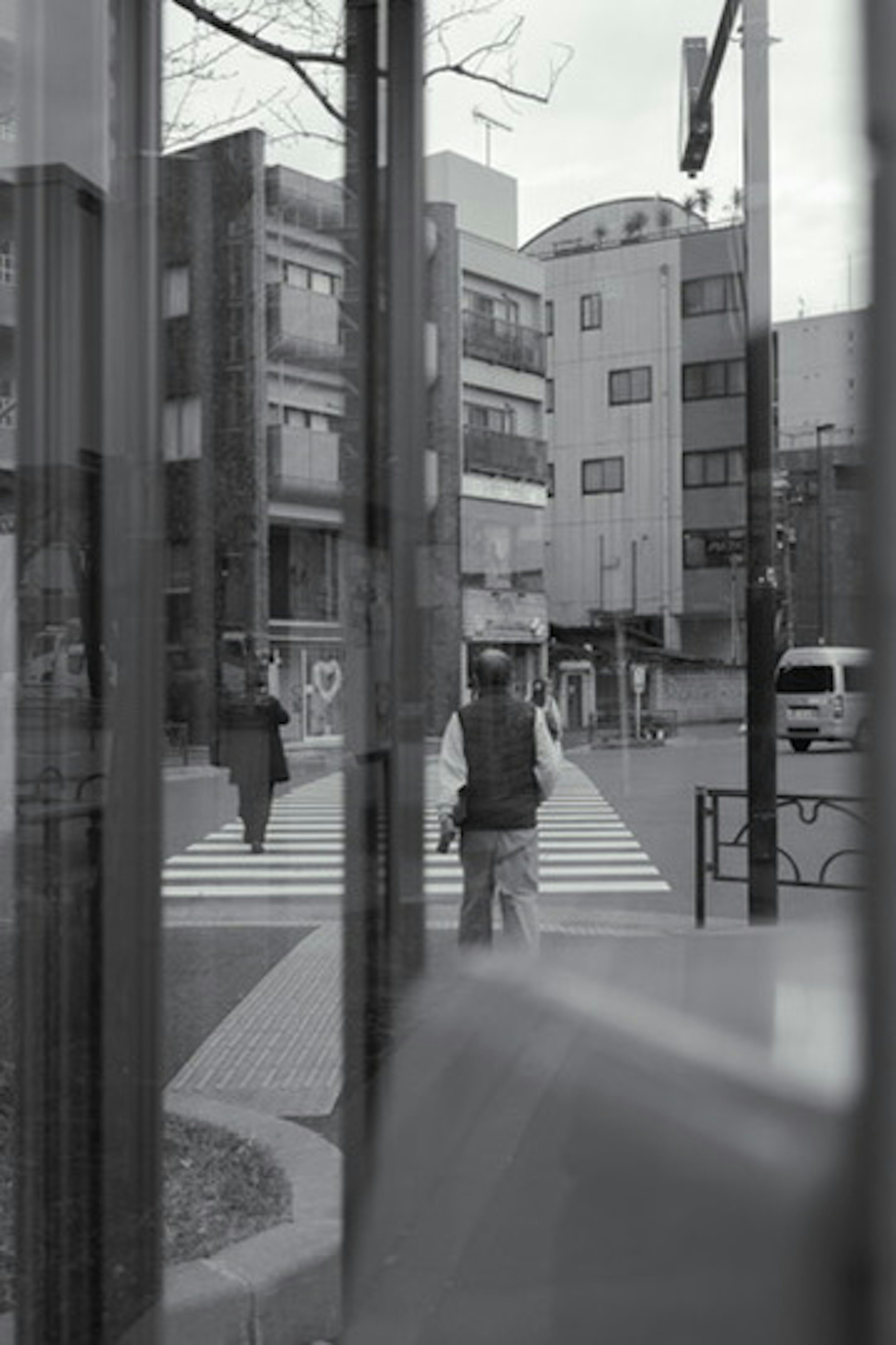 Black and white scene of people crossing a street in an urban area