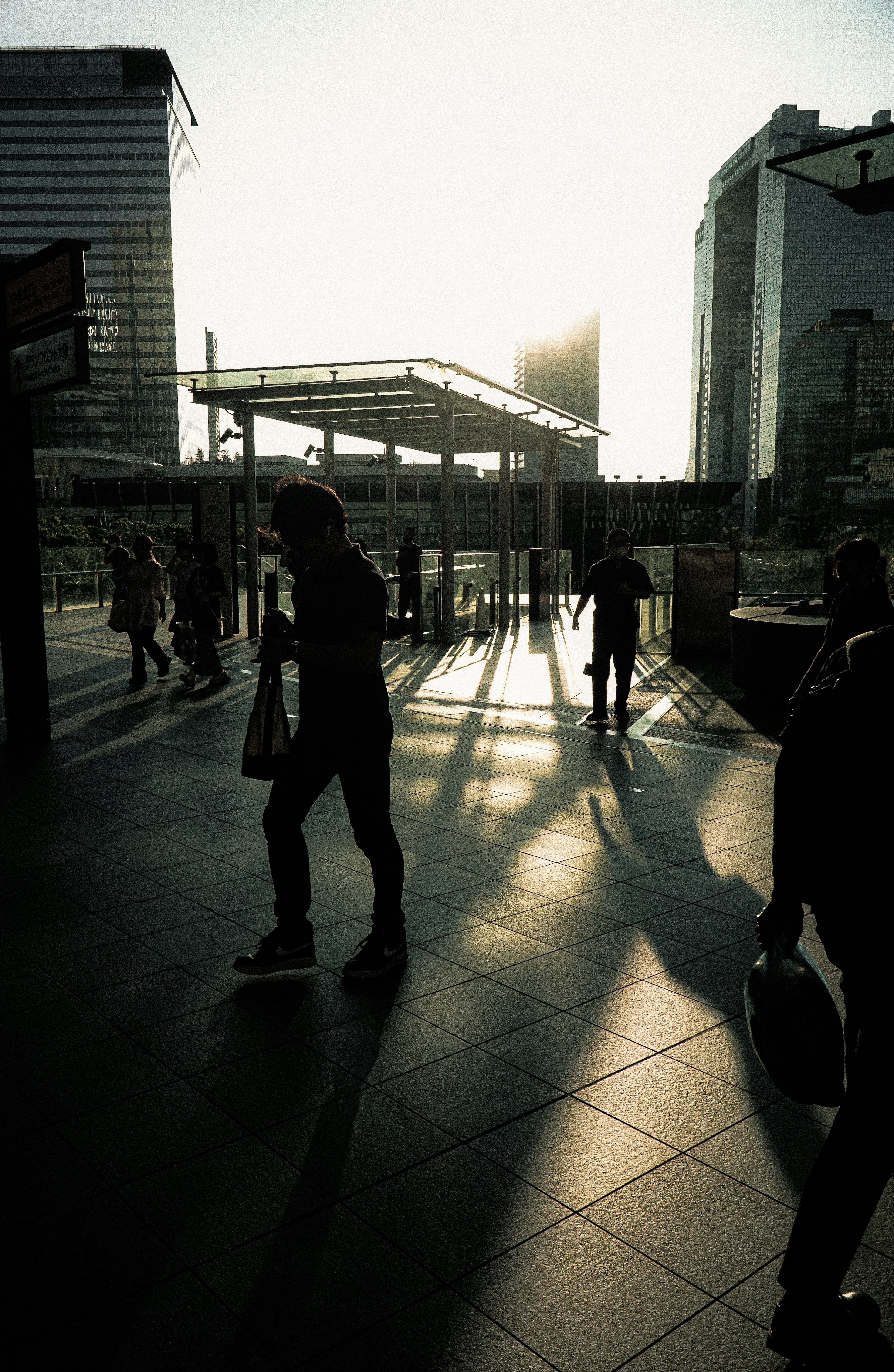 夕日を背景にした都市の風景で人々が歩いているシルエット