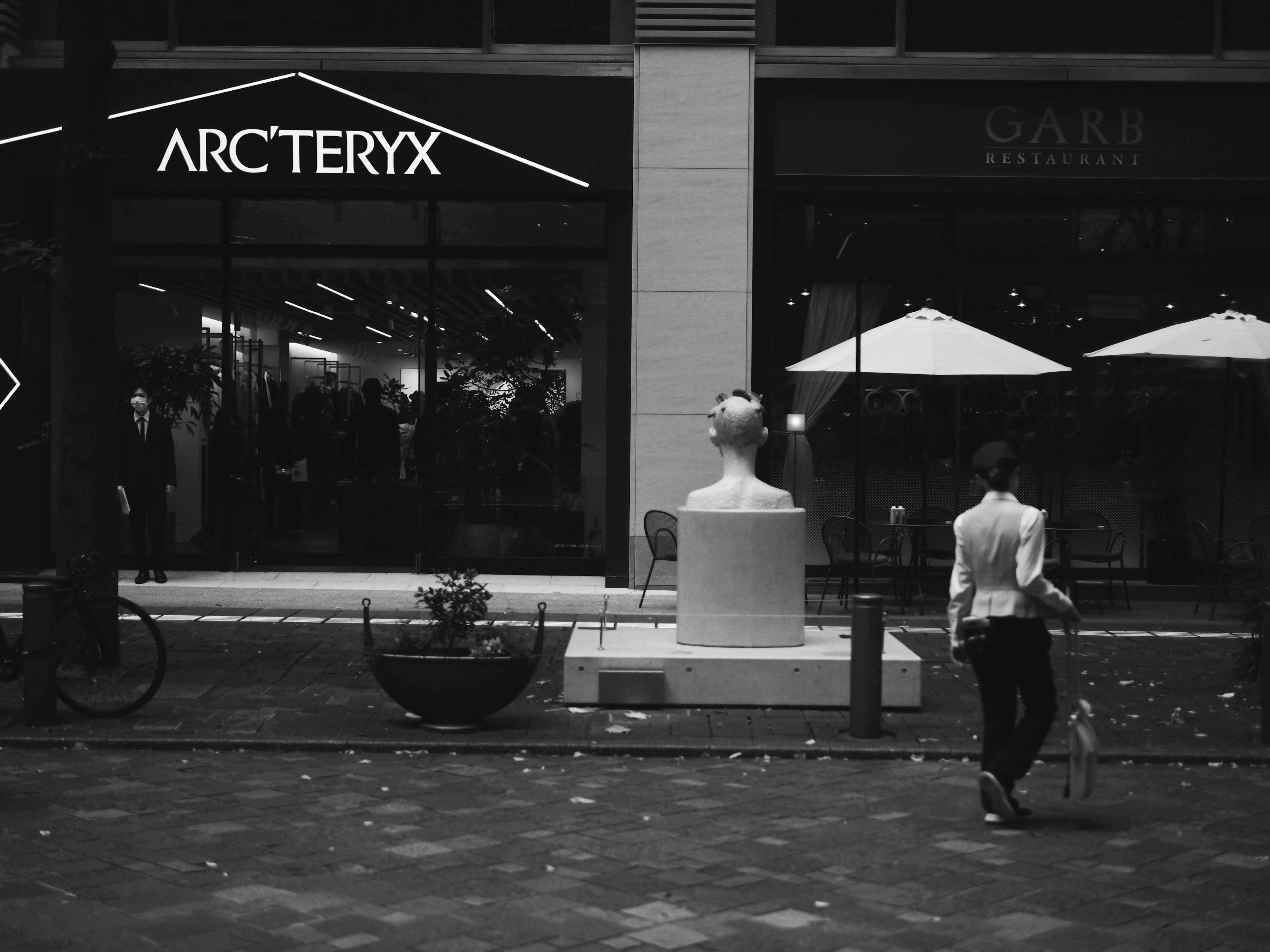 ทิวทัศน์ริมถนนที่มีร้าน Arc'teryx และรูปปั้นสีขาว