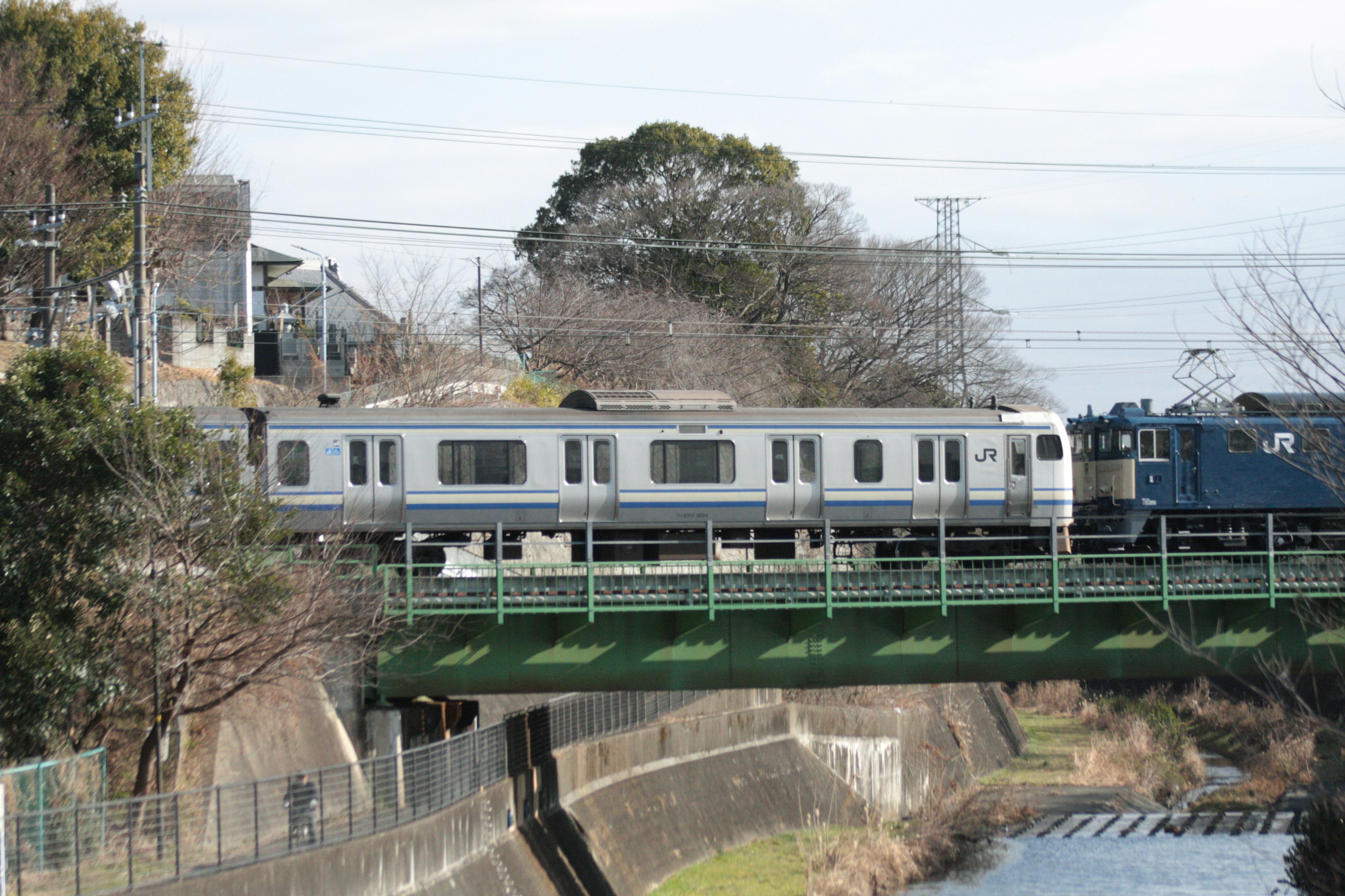 A train crossing a green bridge over a river