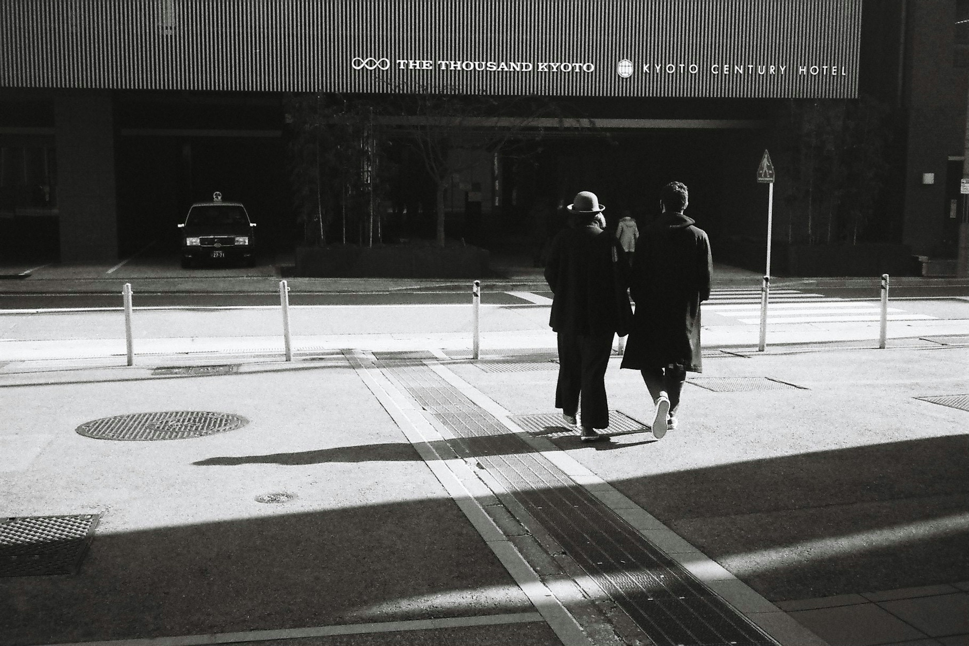 Dos personas con abrigos negros caminando por una calle de la ciudad