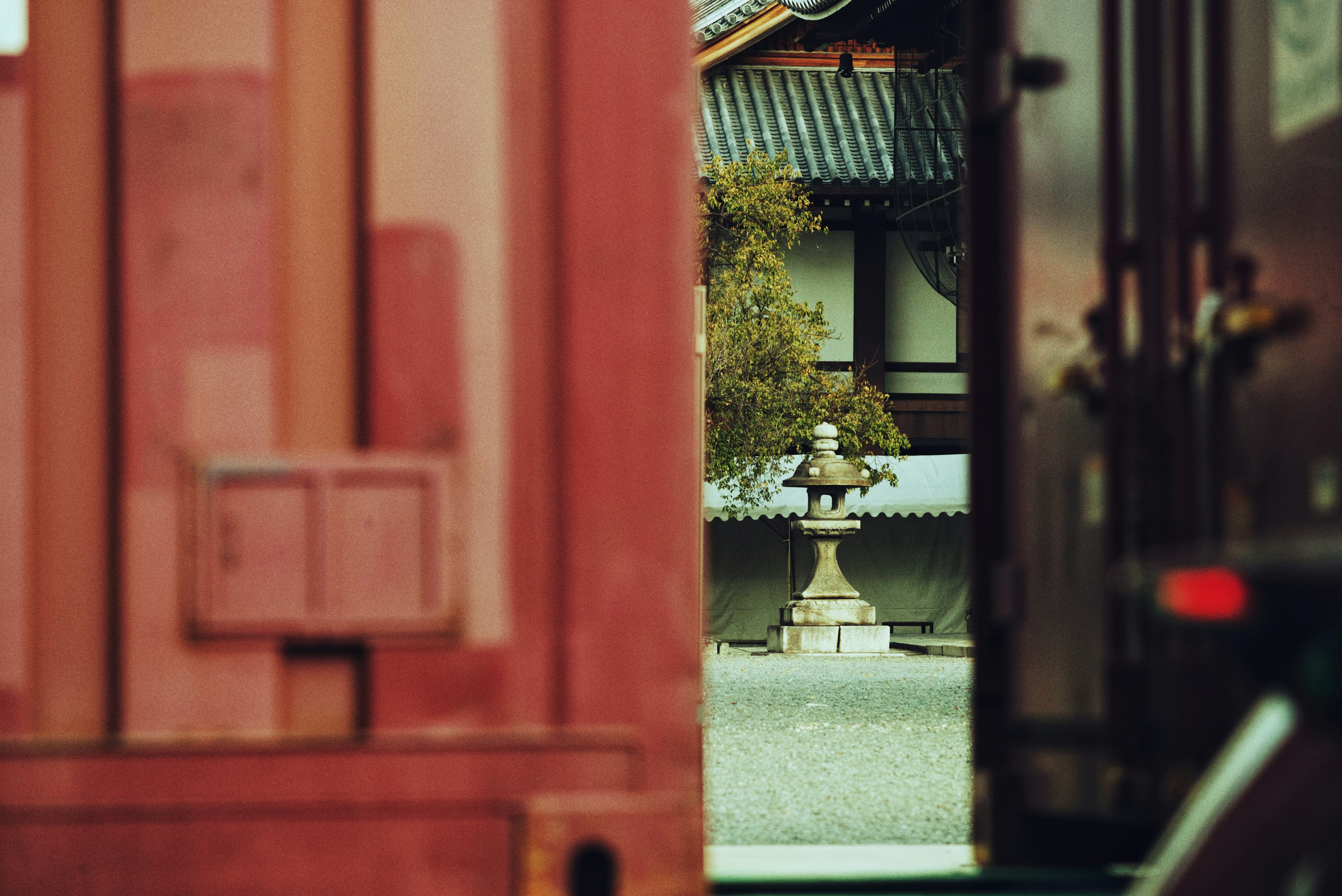 Vue à travers un conteneur rouge montrant un jardin japonais et une lanterne en pierre