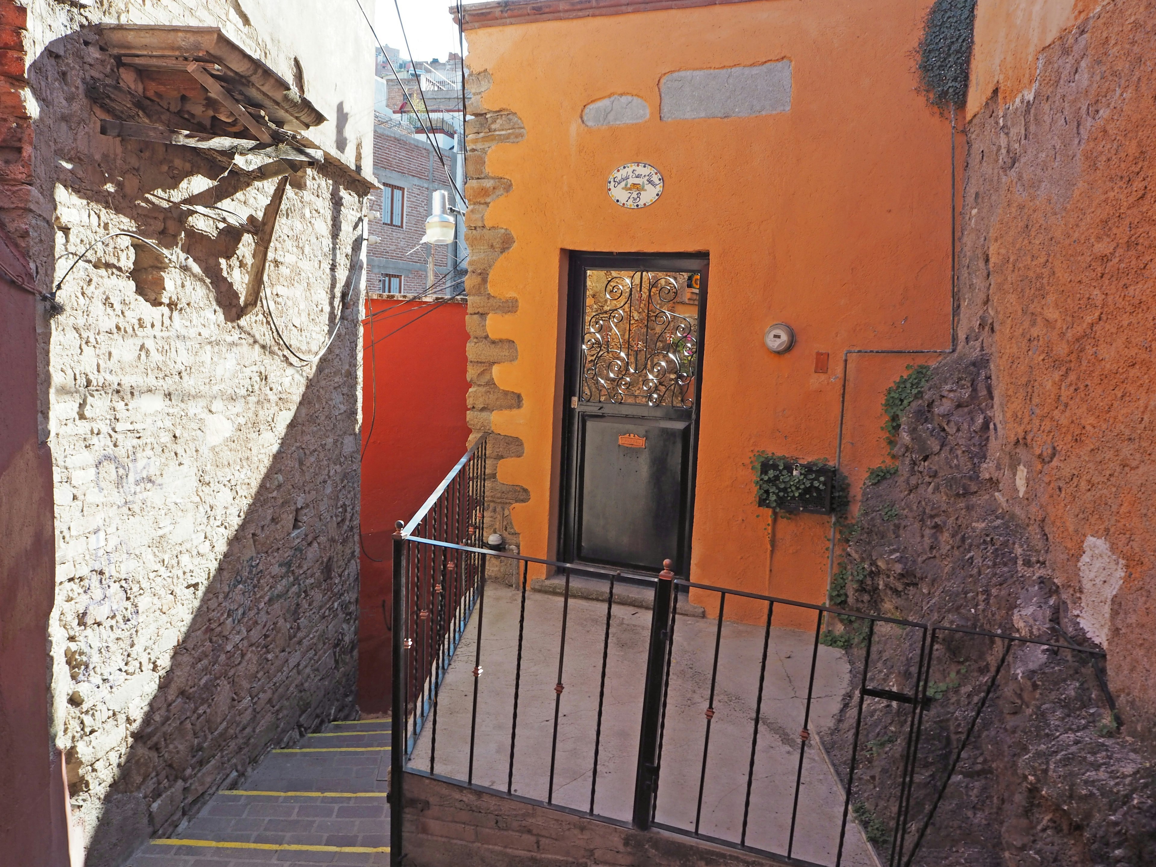 Scène de rue étroite avec une maison orange et des escaliers