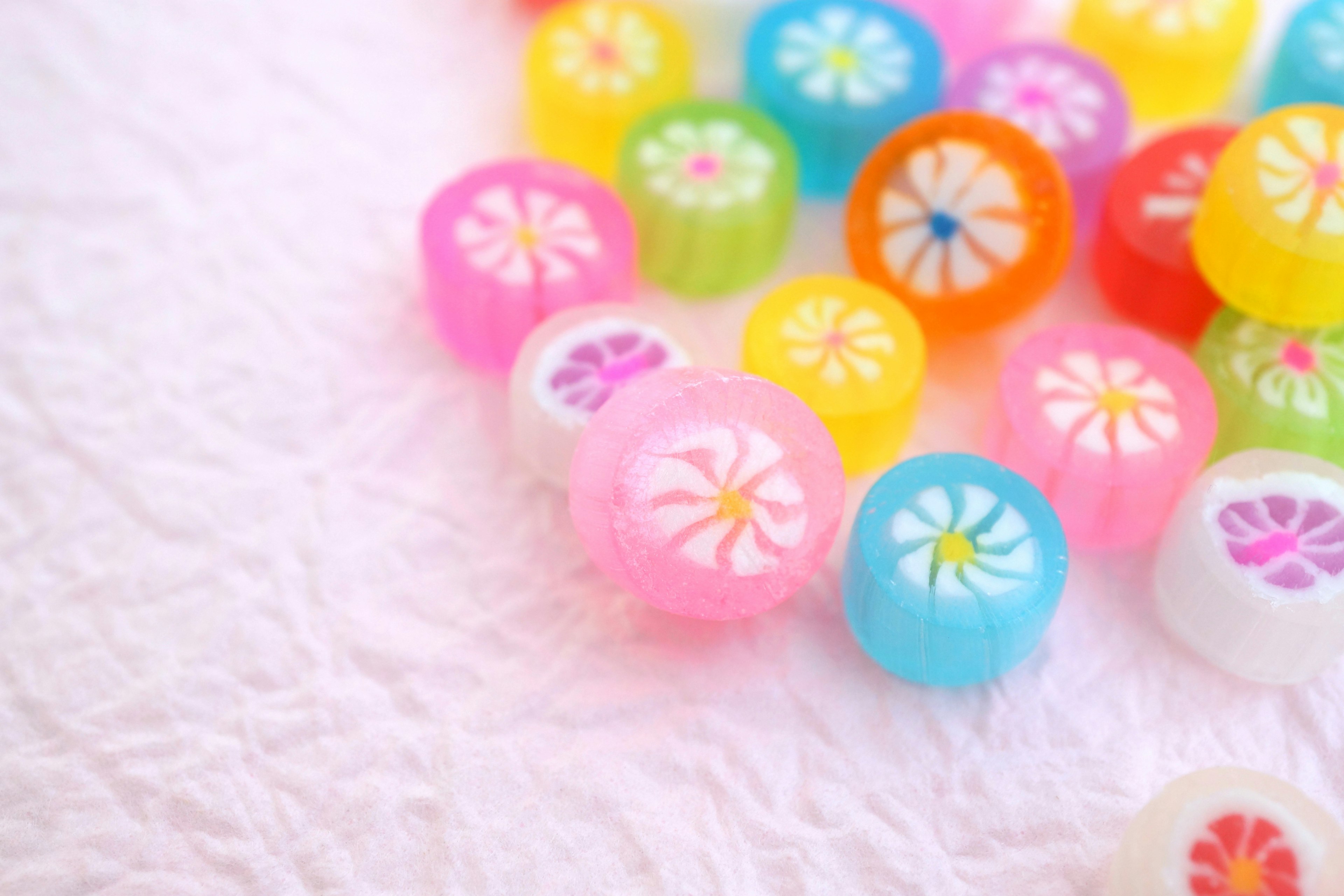 Bunte Bonbons mit Blumenmustern, die auf einem weißen Stoff verstreut sind